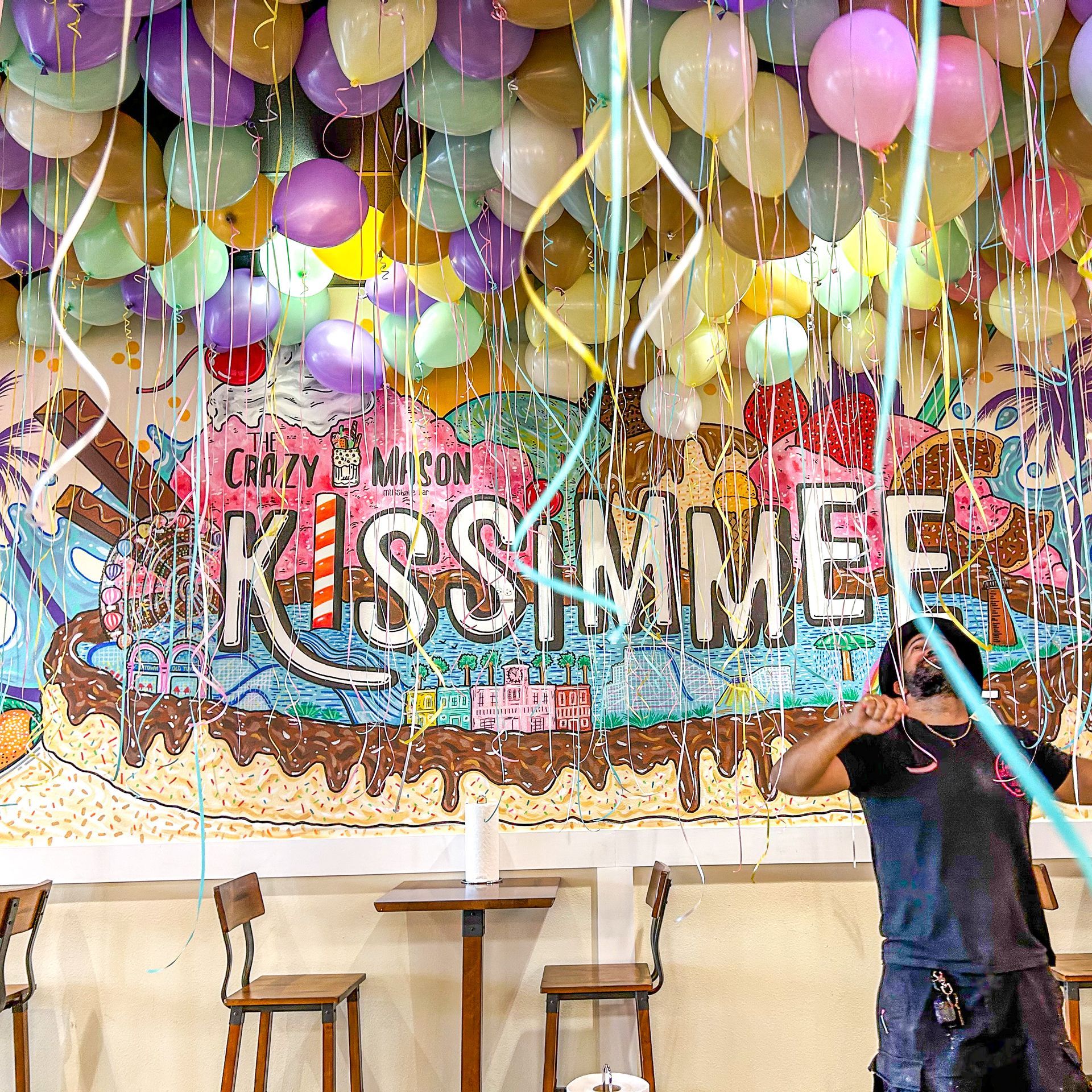 A man stands in front of a mural that says kissimmee