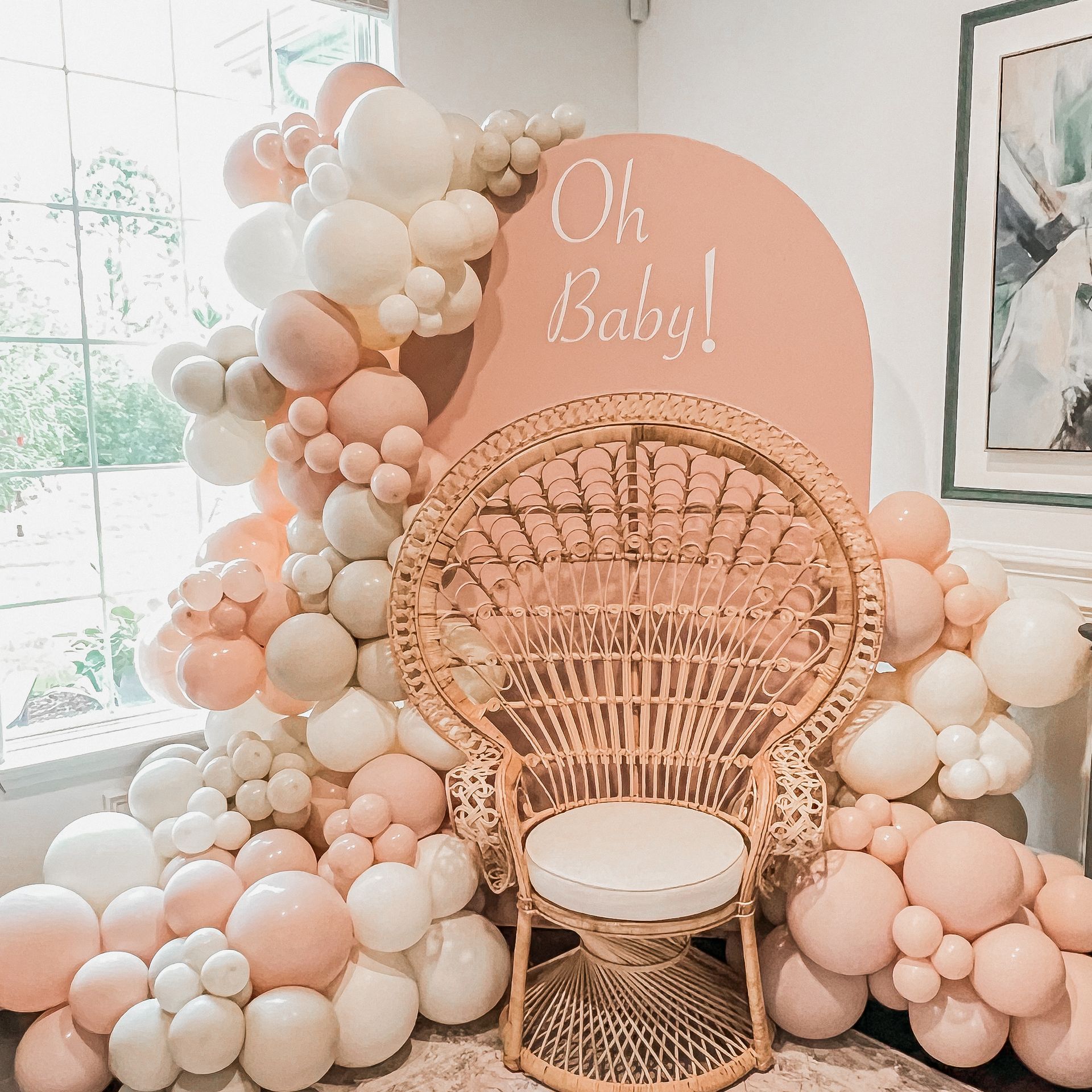 a wicker chair is surrounded by balloons for a baby shower .