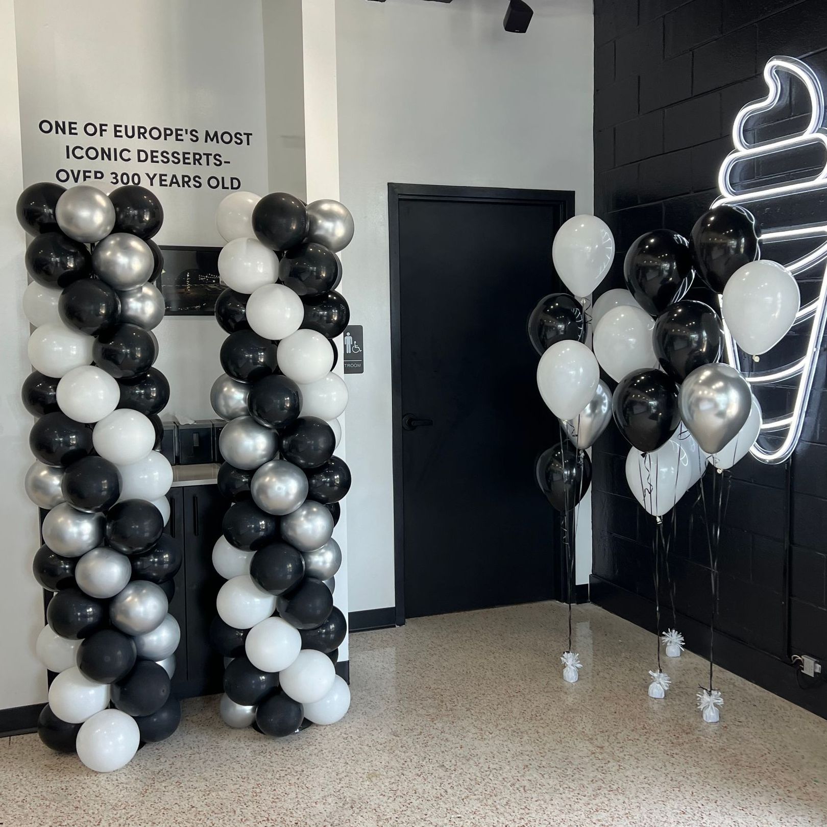 A room with balloons and a sign that says one of europe 's most iconic desserts over 30 years old