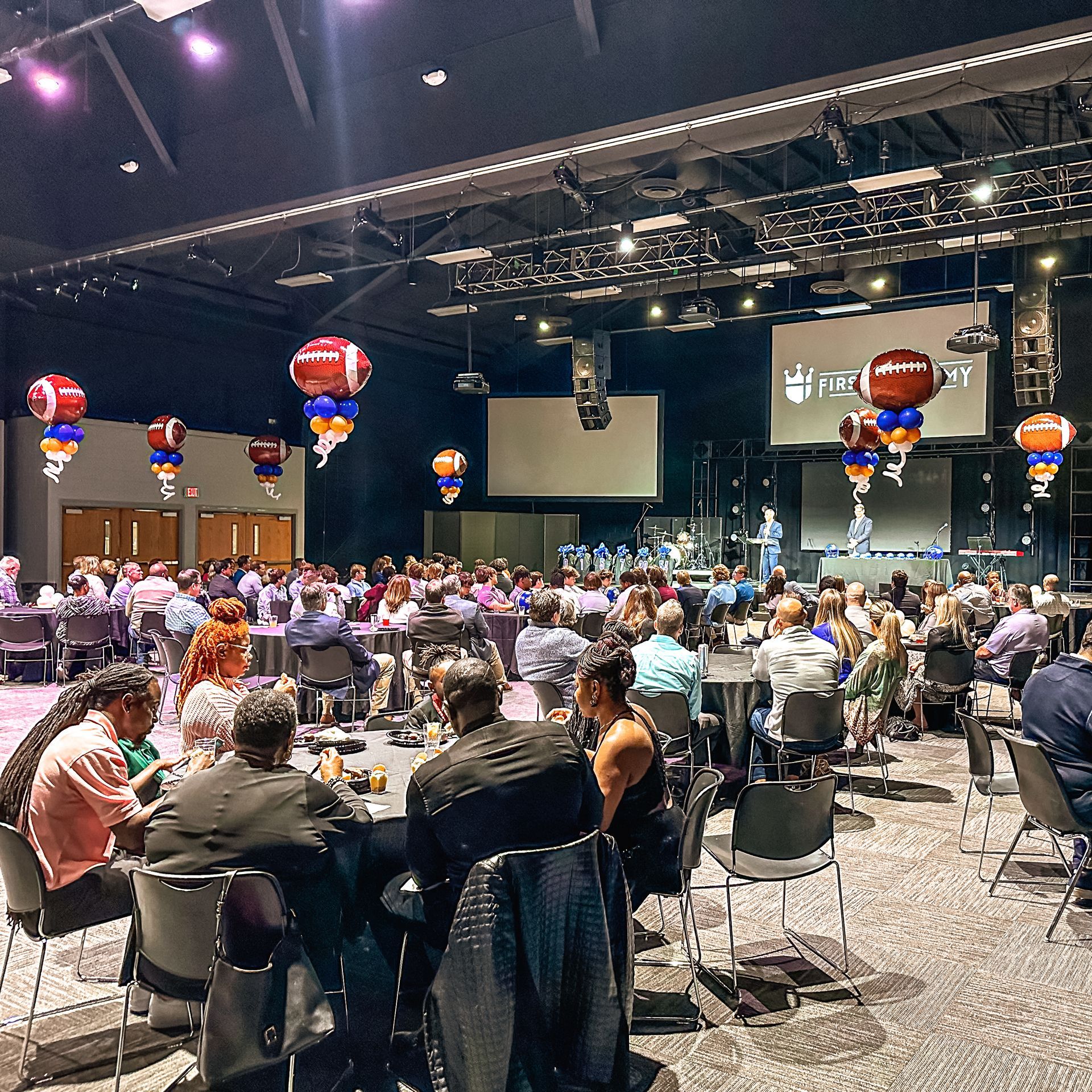 A large room filled with people sitting at tables and chairs