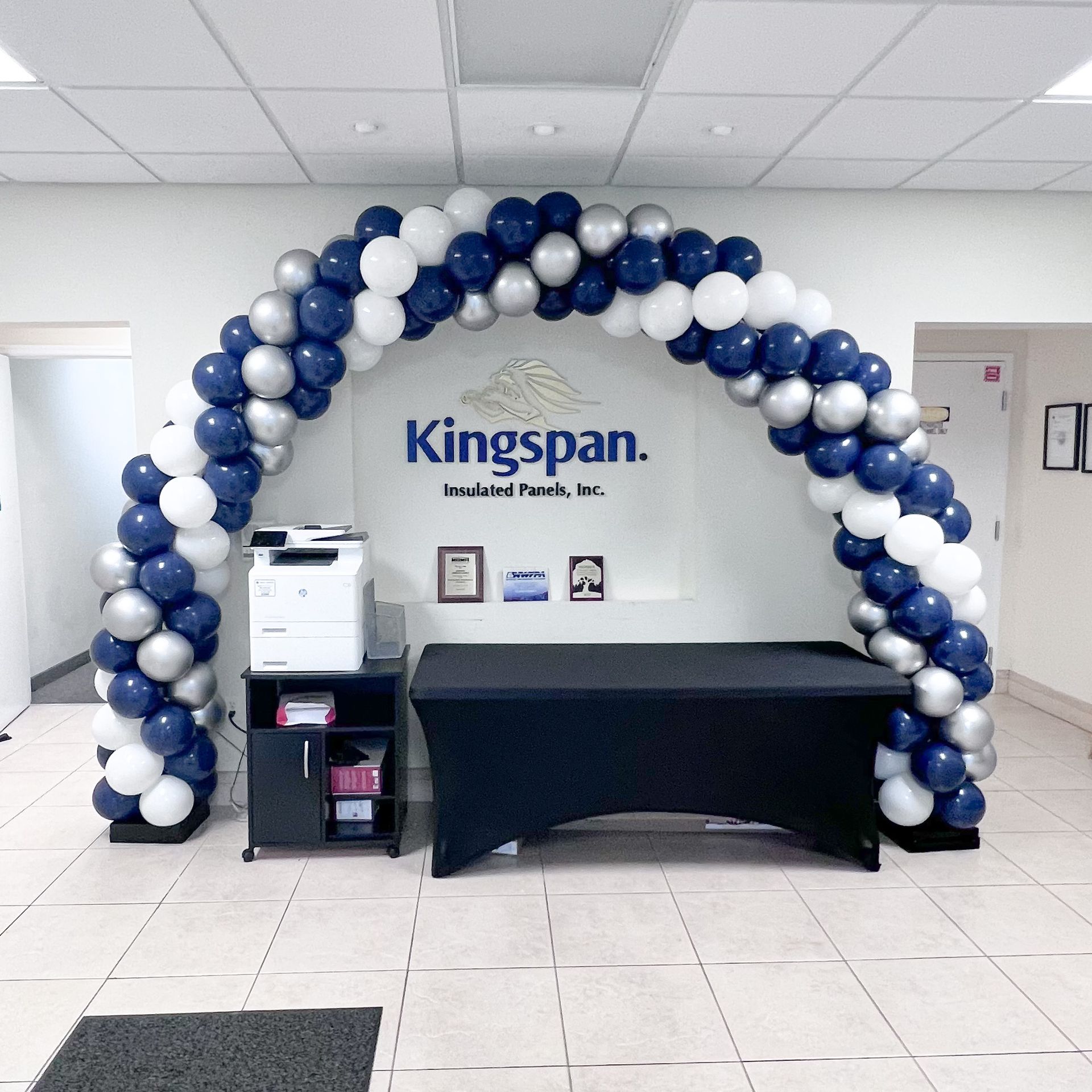 A blue and white balloon arch in front of a kingspan sign