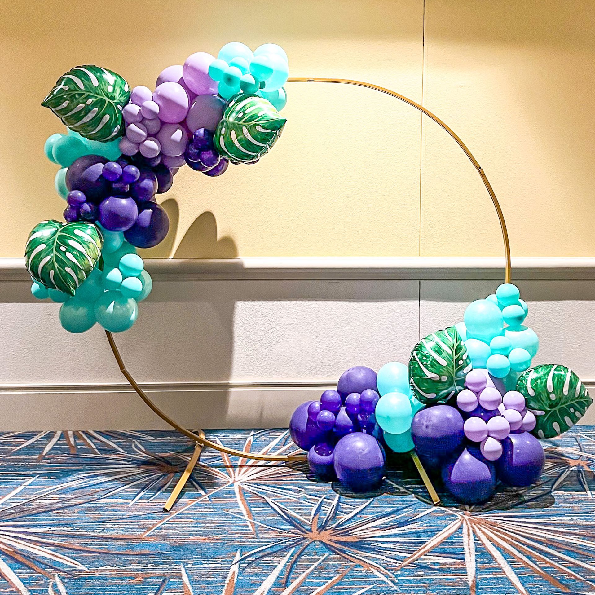 A circle filled with balloons and leaves is sitting on a blue carpet.