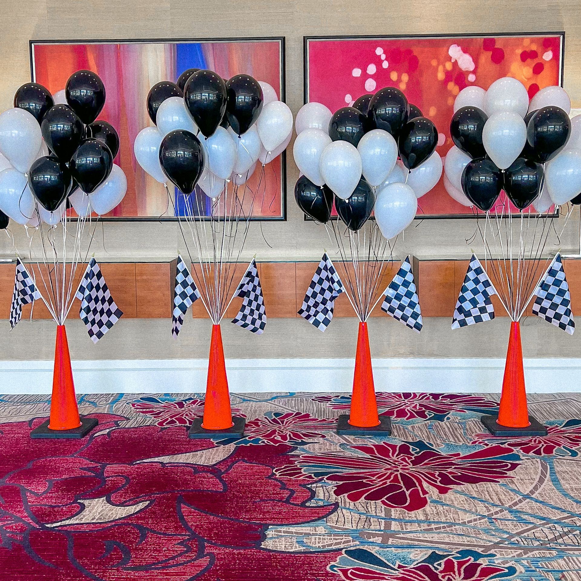 a bunch of black and white balloons are sitting on top of orange cones .