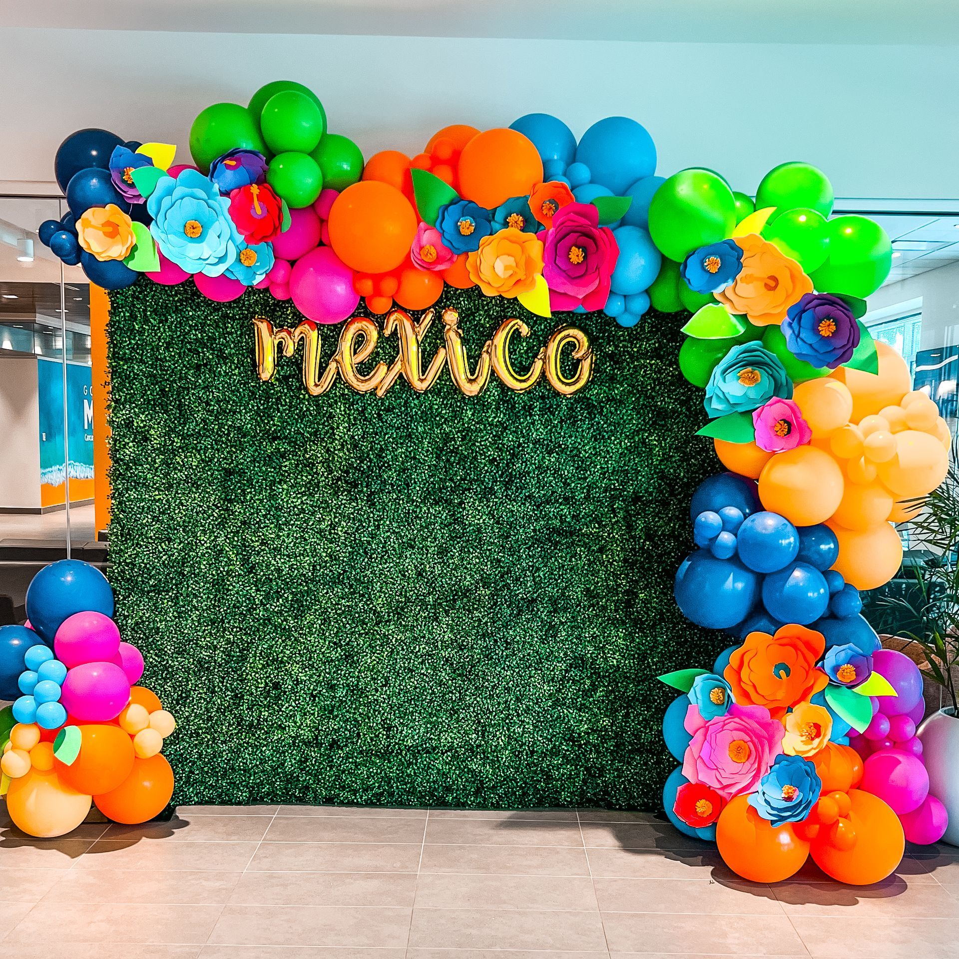 A wall decorated with balloons and flowers with the word mexico on it