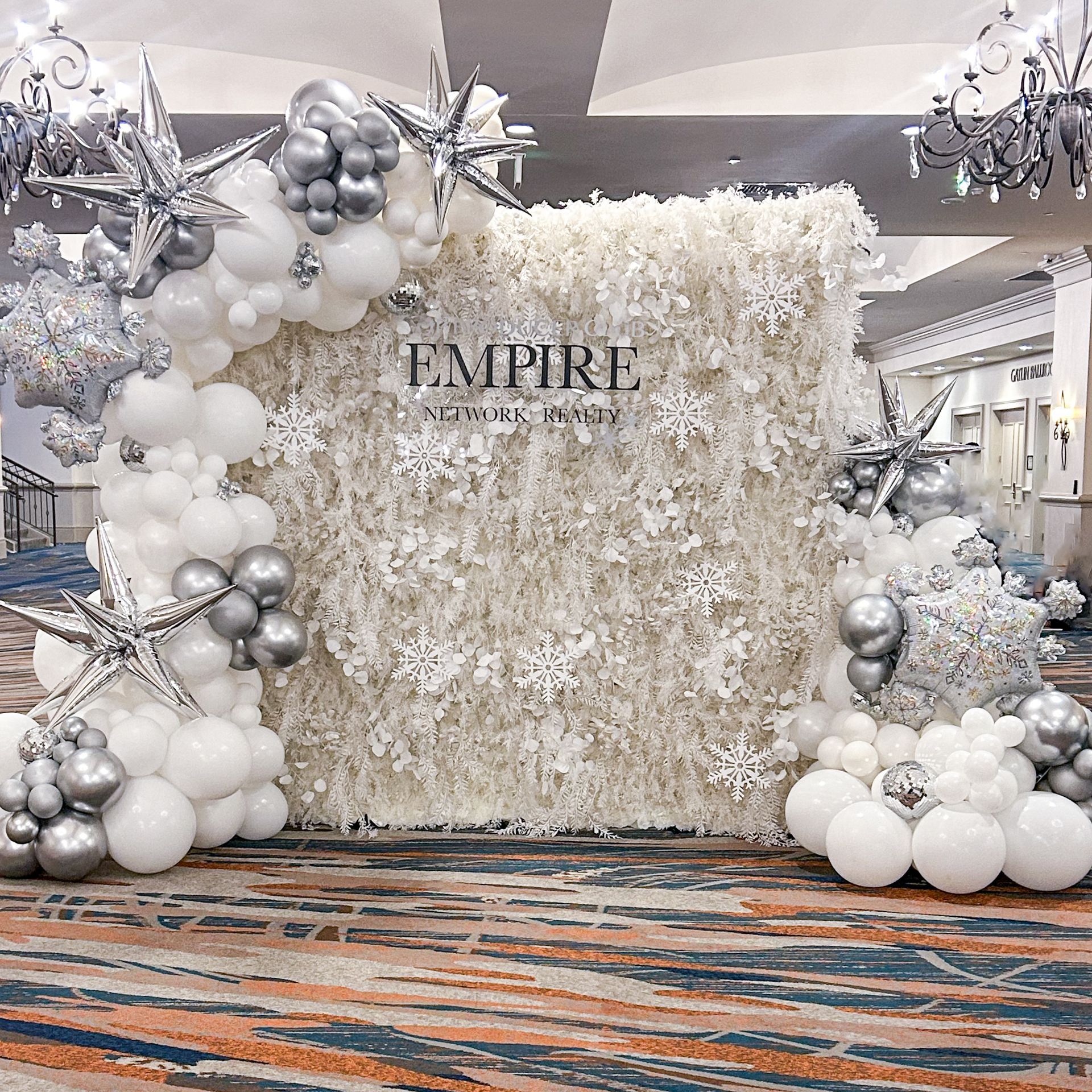 A wall covered in white and silver balloons and snowflakes.