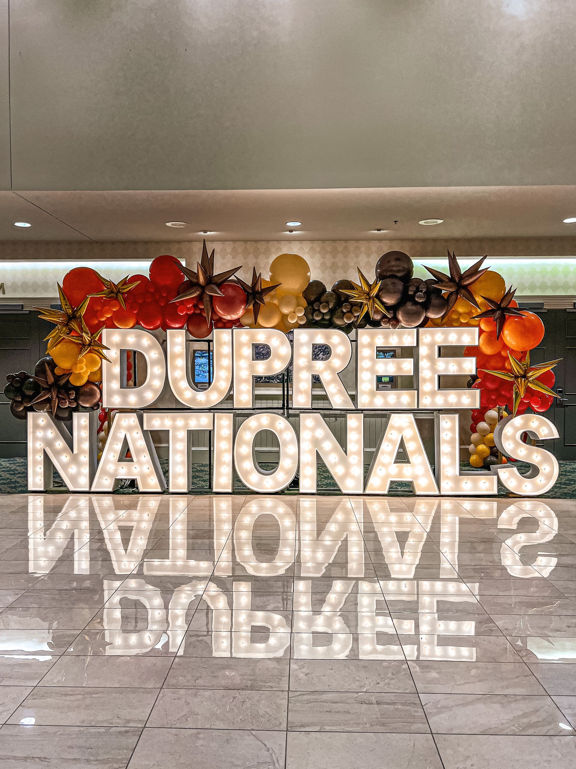A sign that says dupree nationals is surrounded by balloons and flowers.