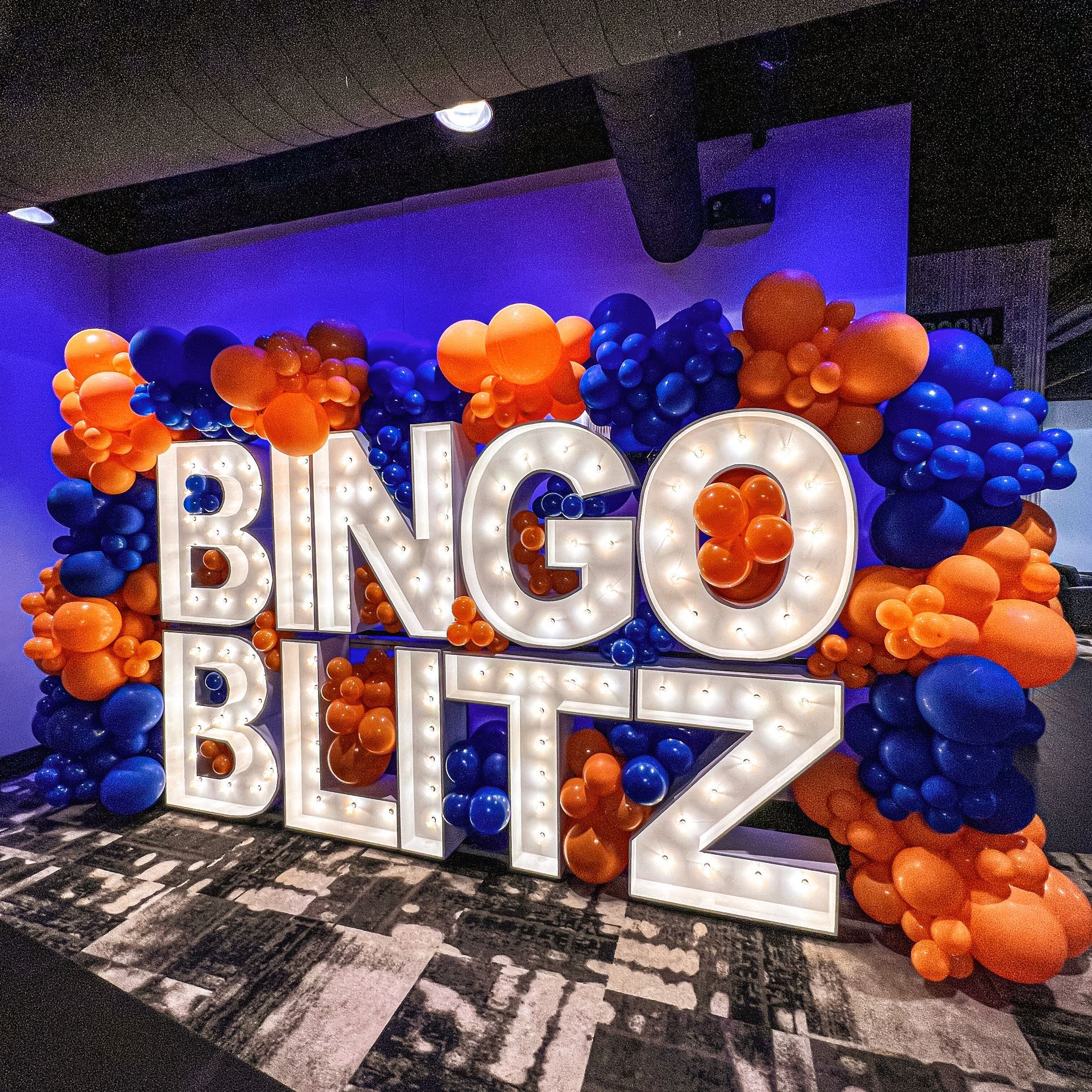 A large sign that says bingo blitz is surrounded by balloons.