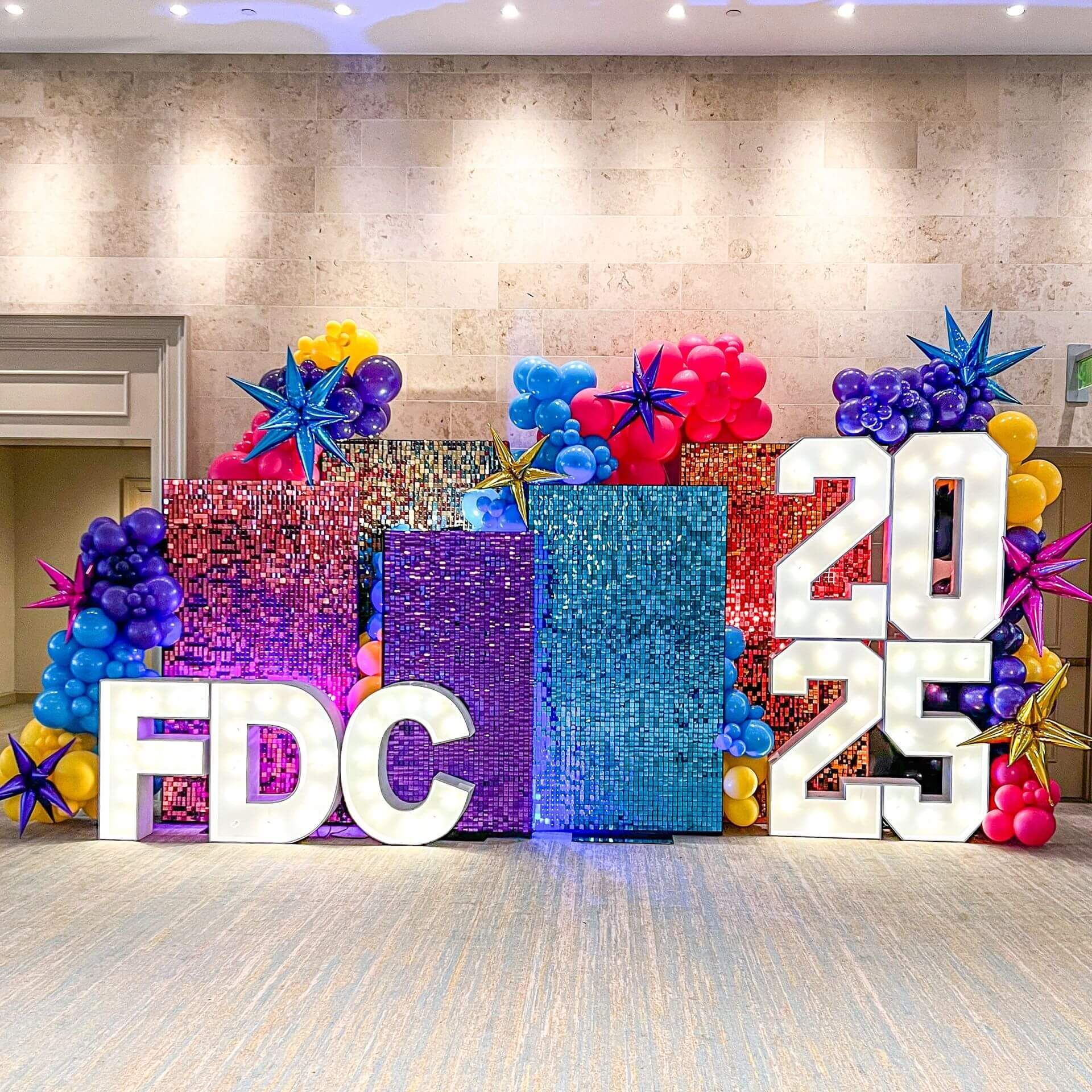 A large sign that says fdc is surrounded by balloons and lights.