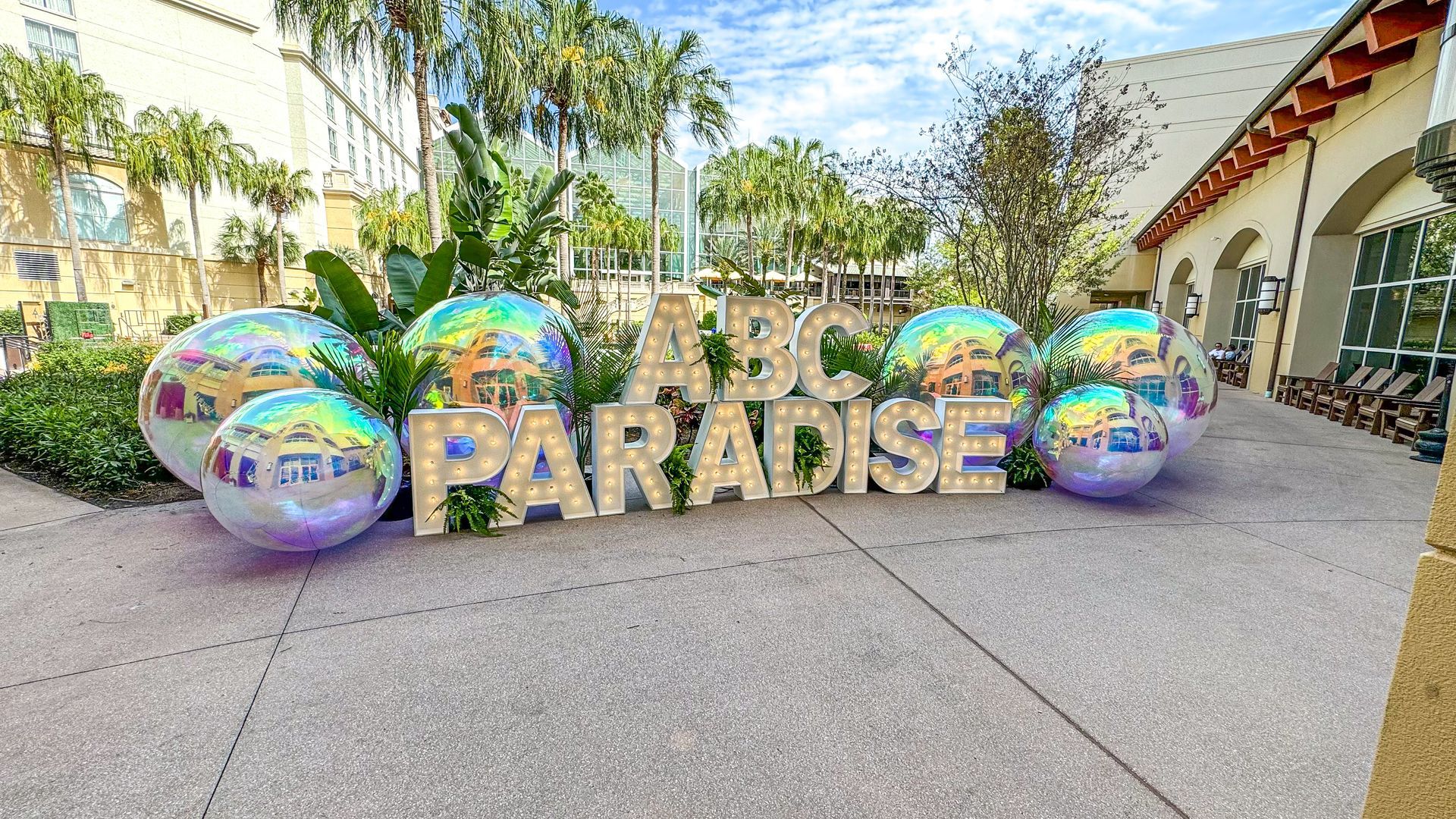 A sign that says abc paradise is surrounded by balloons.