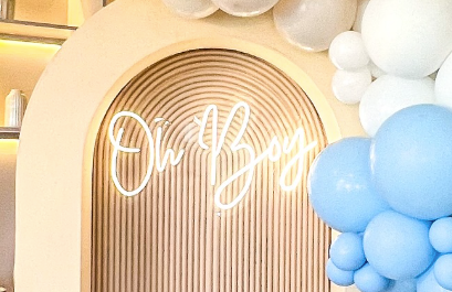 A wooden arch with balloons and a neon sign that says