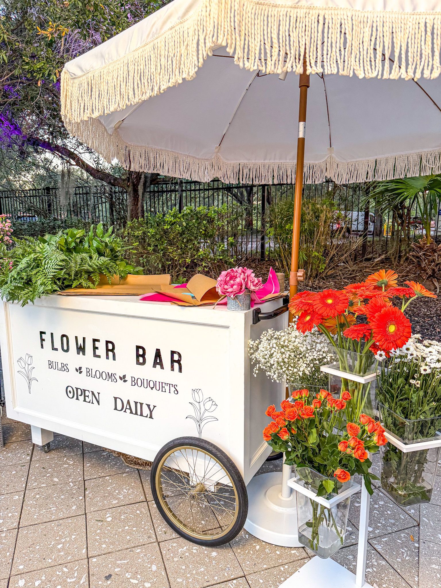 Flower cart with a white umbrella, offering colorful blooms.