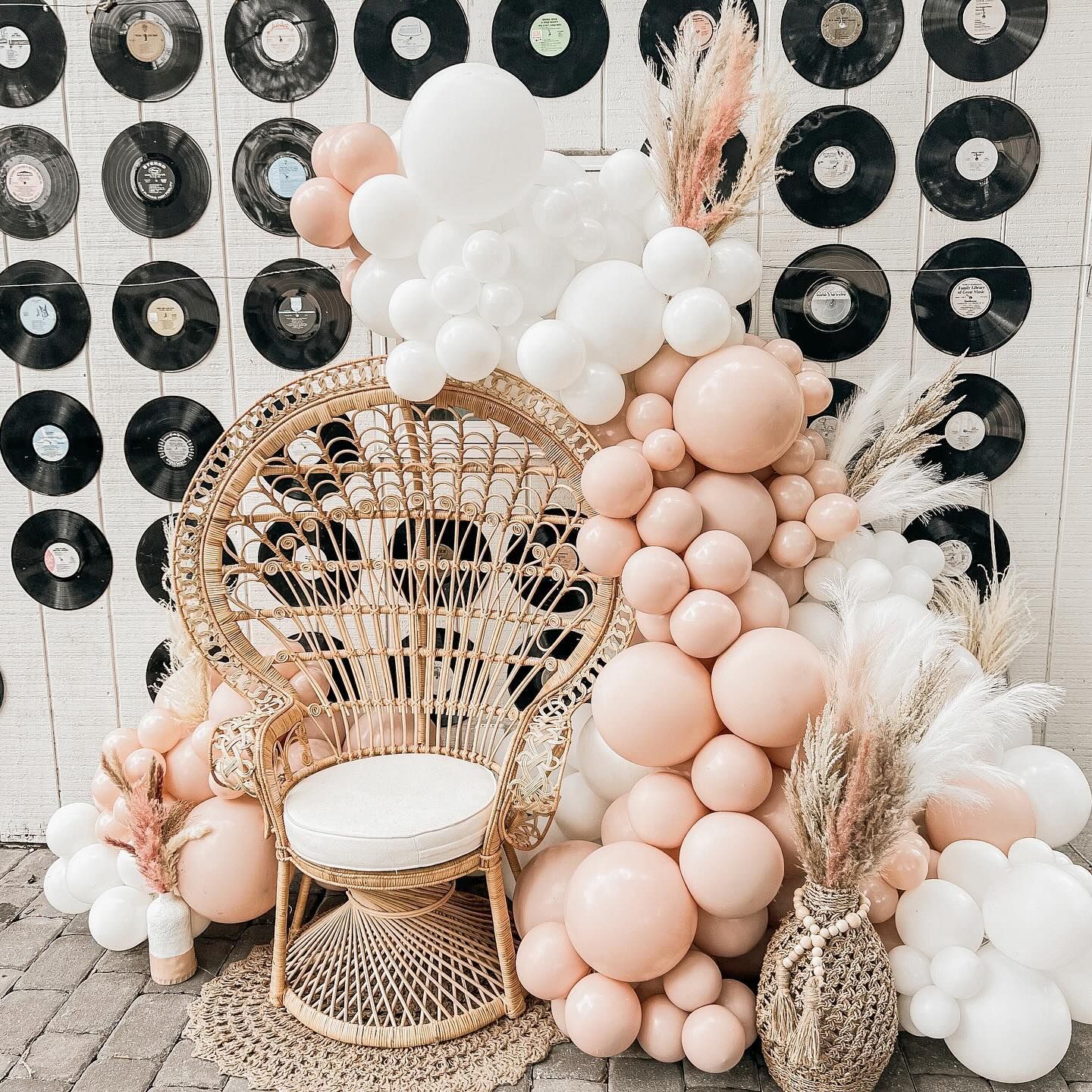 A wicker chair is surrounded by balloons and records.