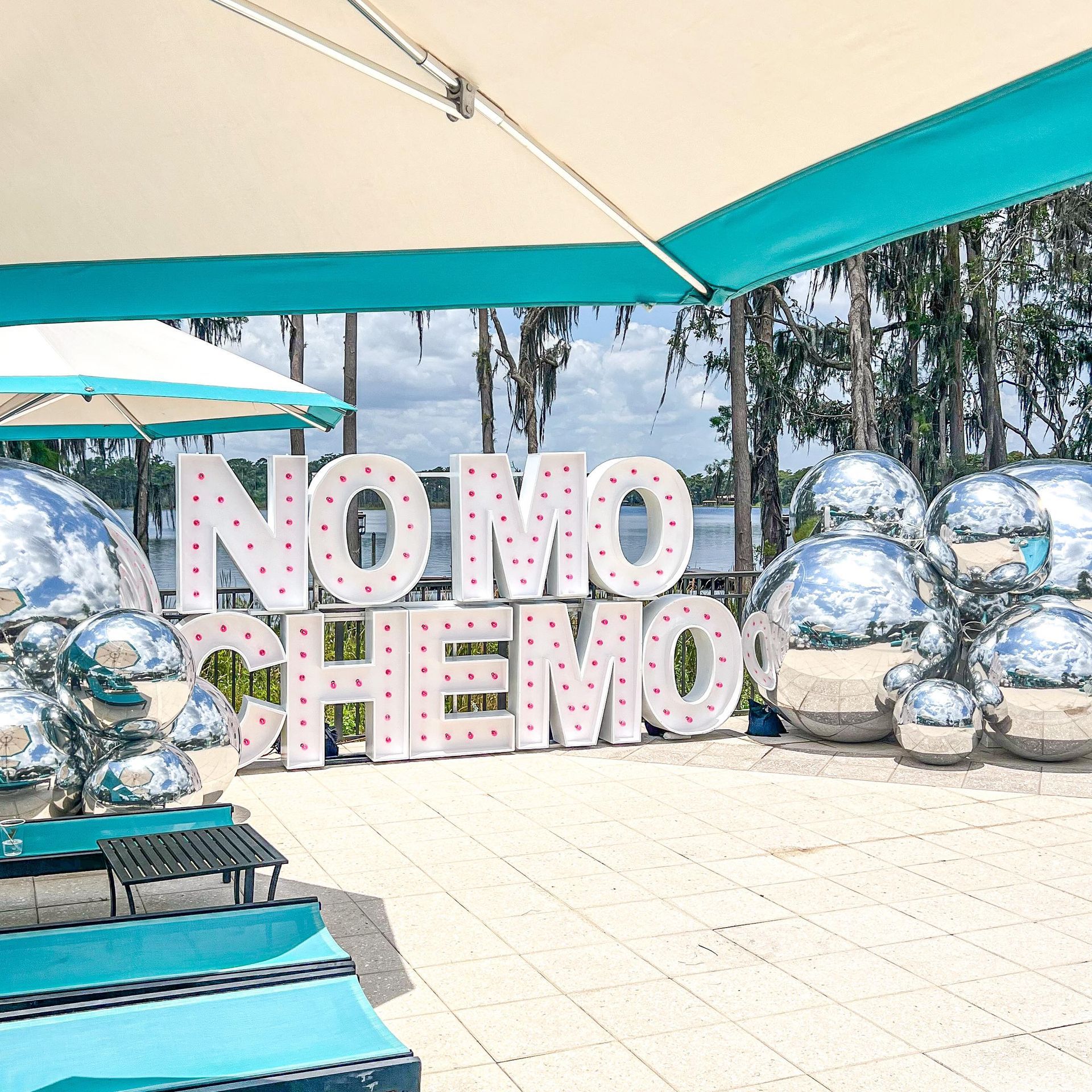 A sign that says ' no more chemo ' is surrounded by balloons and umbrellas.