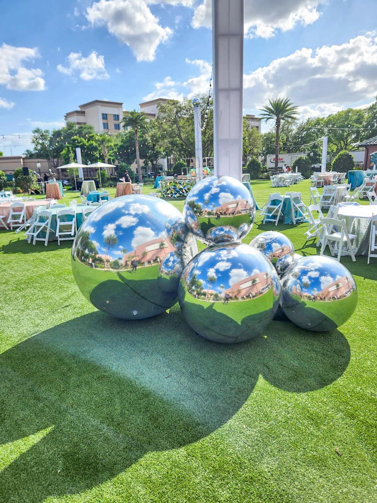 A bunch of silver balls are sitting on top of a lush green field.
