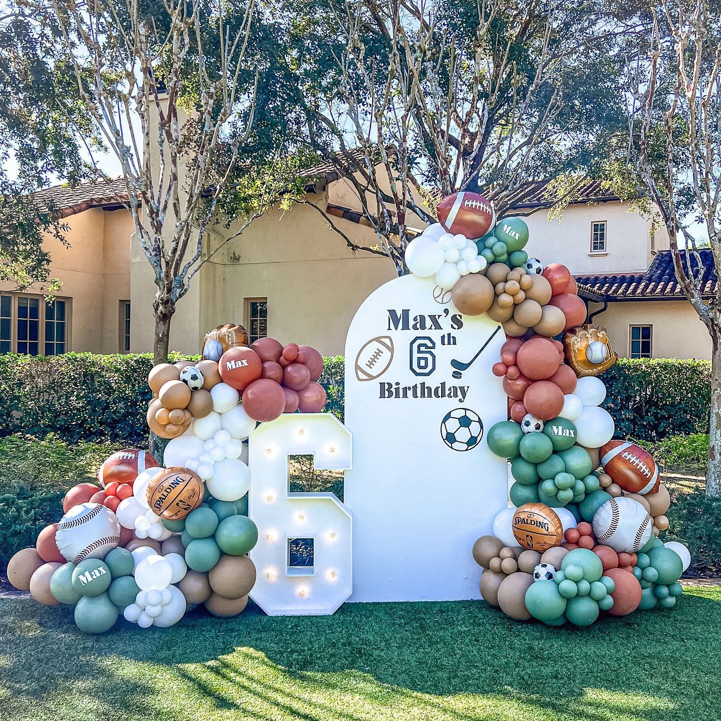 A bunch of balloons are sitting on the grass in front of a house.