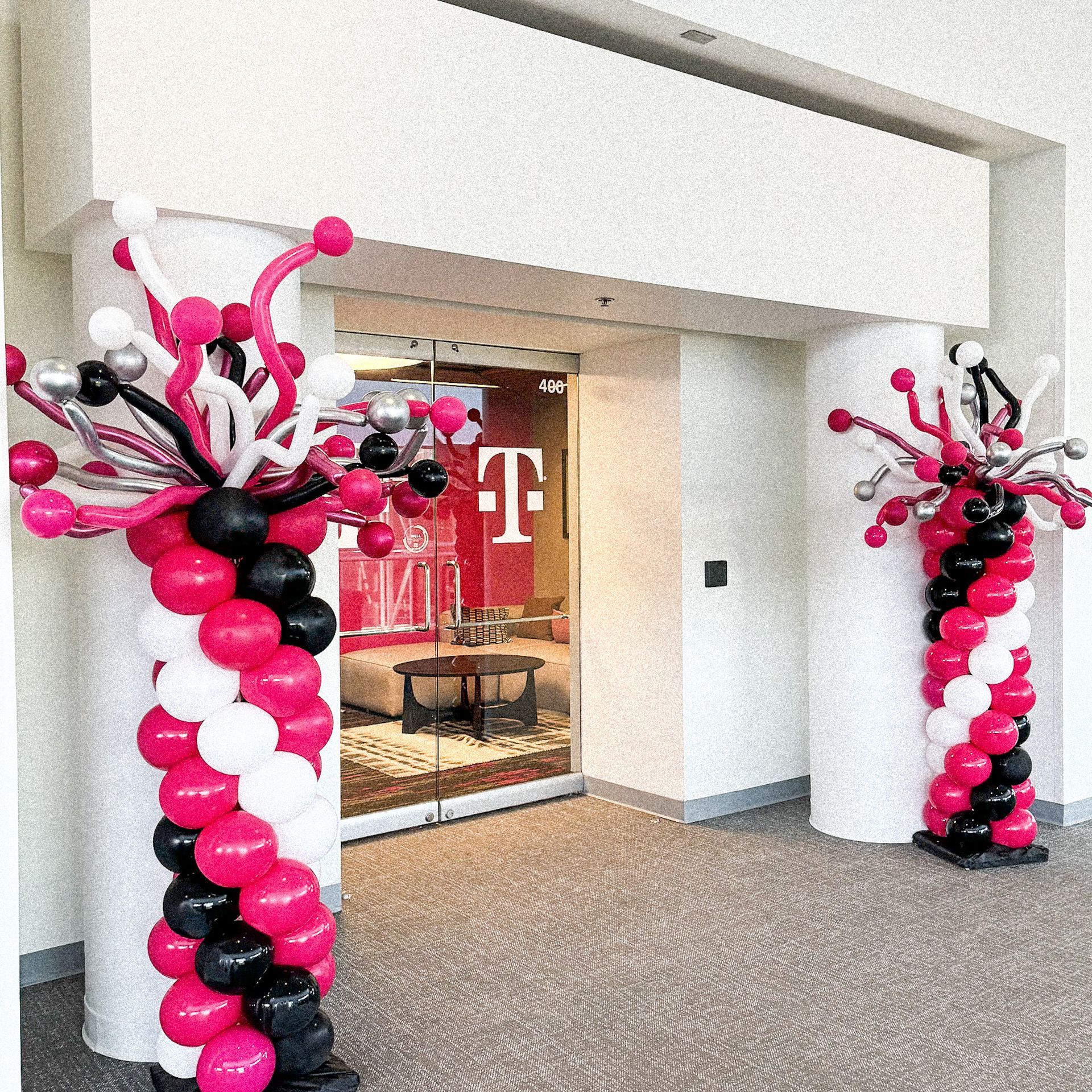 A t-mobile store is decorated with pink and black balloons