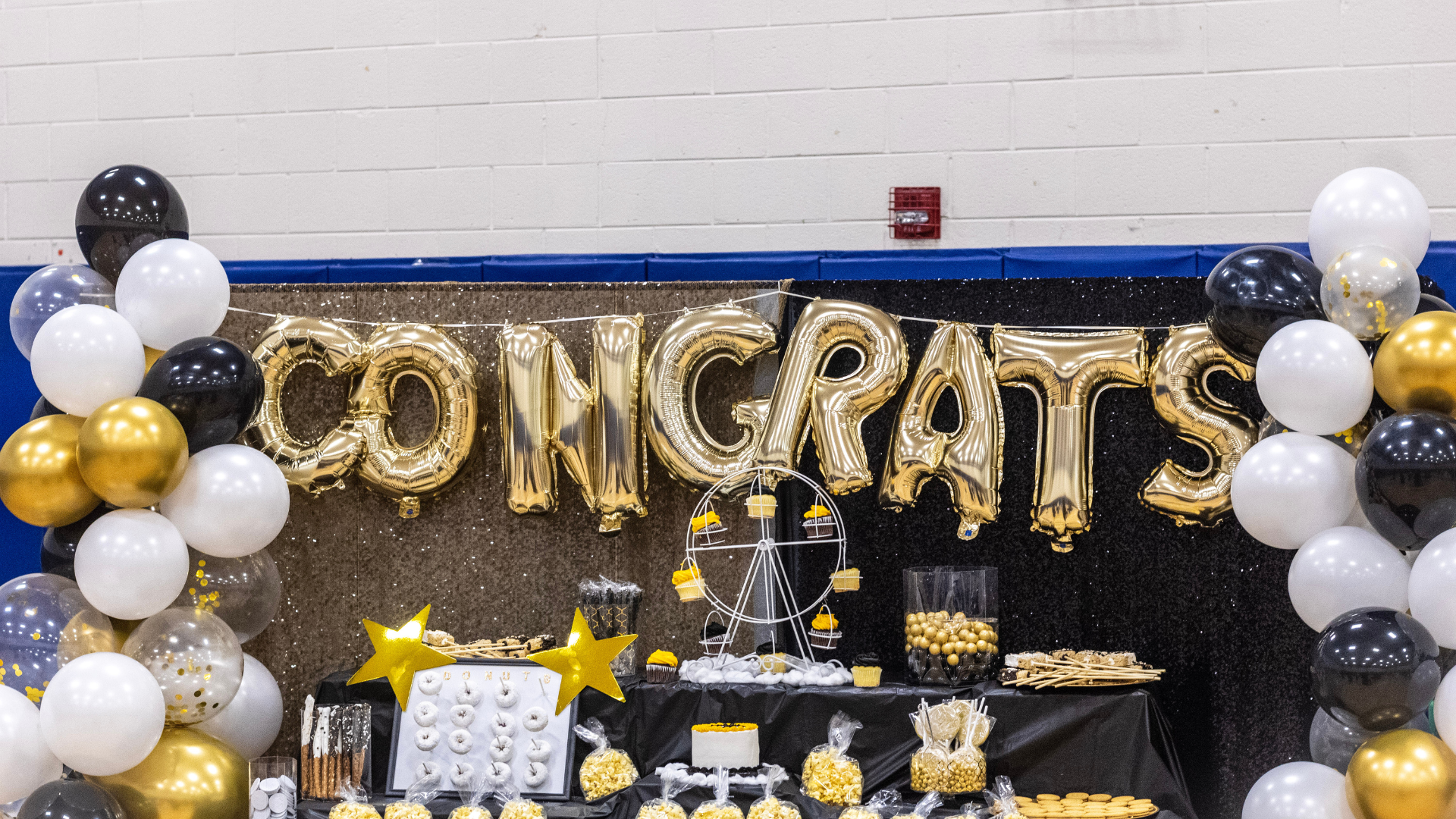 A table decorated with balloons and a sign that says `` congrats ''.