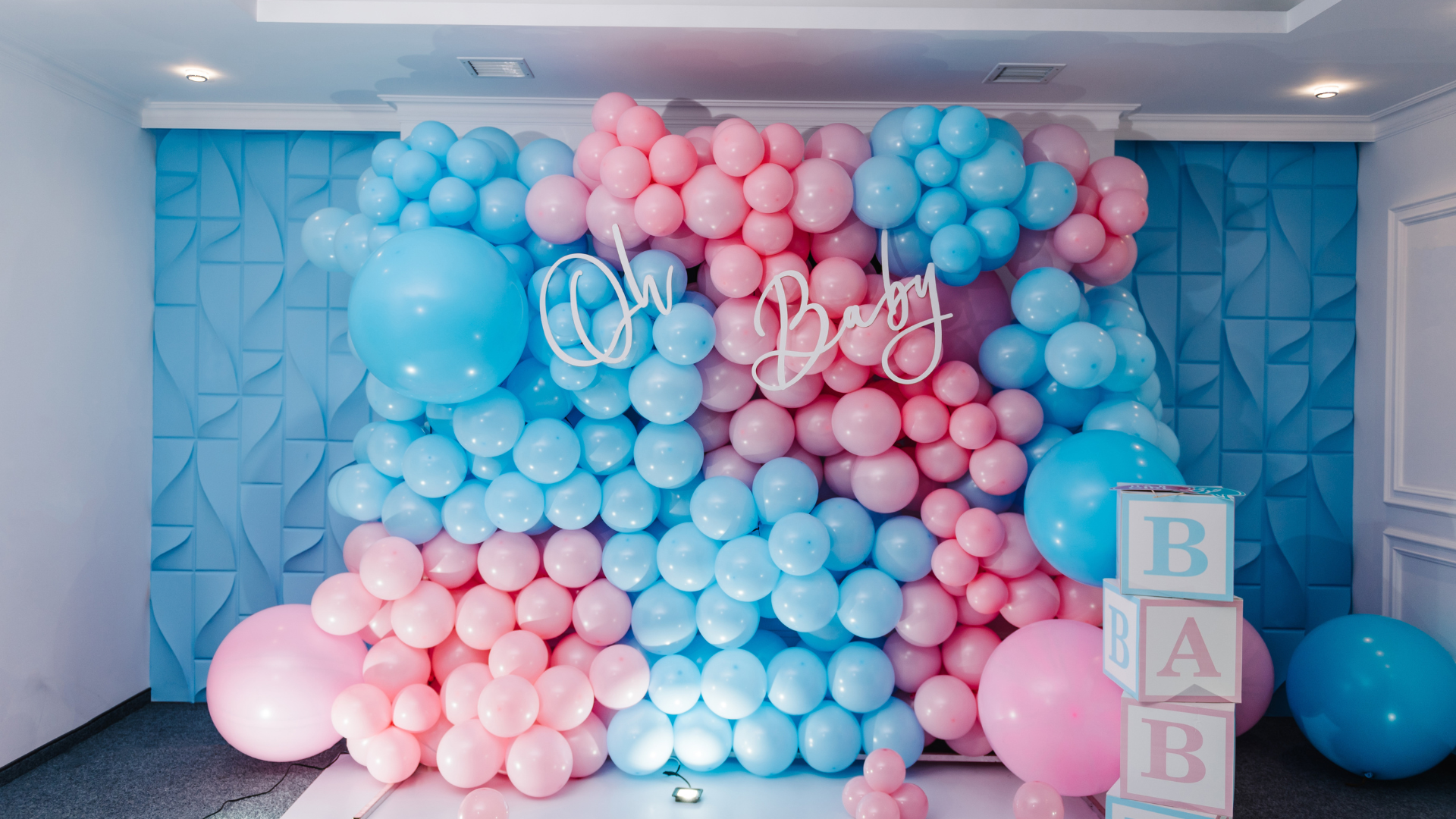 A wall of pink and blue balloons for a baby shower.