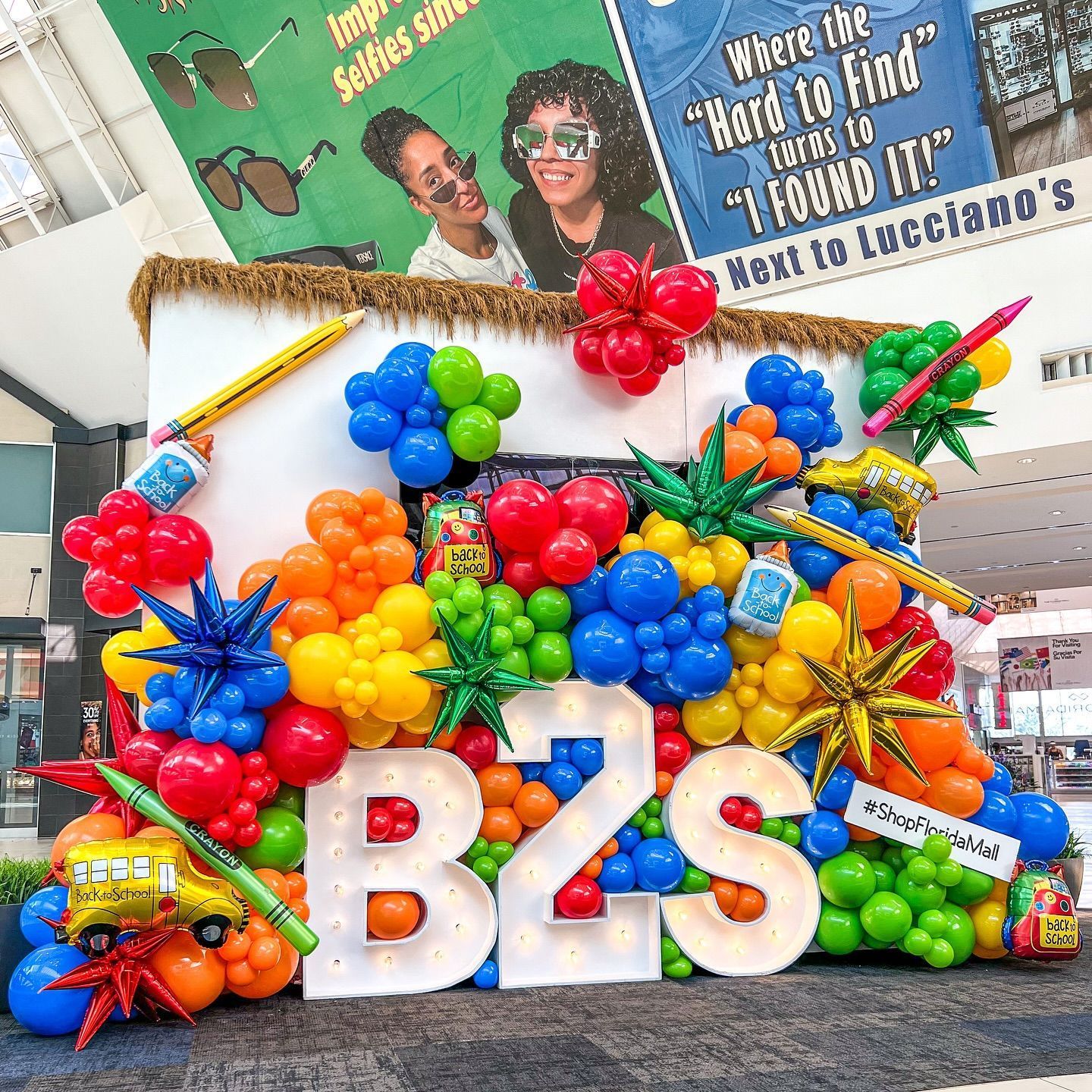 A large b2s sign is surrounded by colorful balloons.