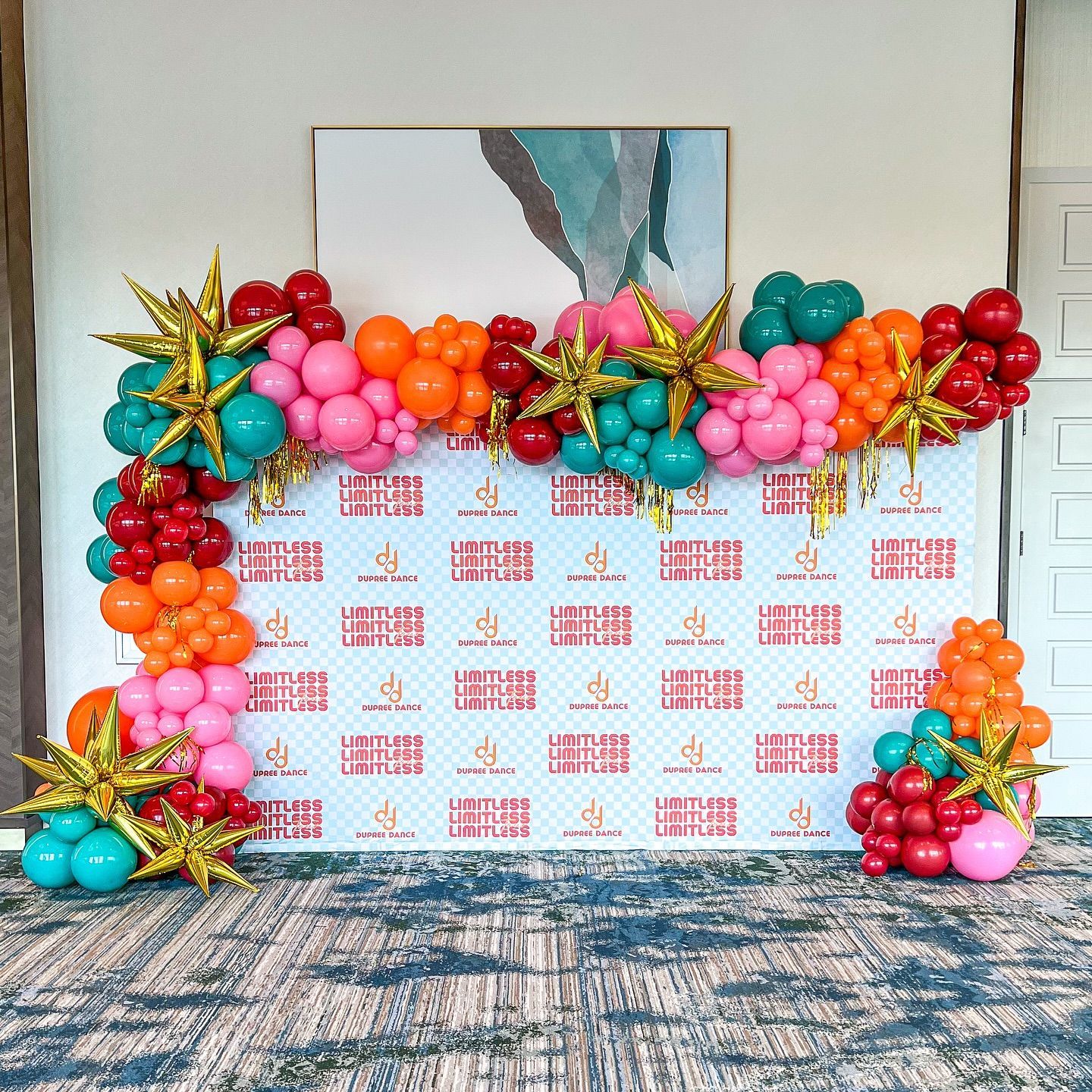 A wall covered in colorful balloons and foil stars.