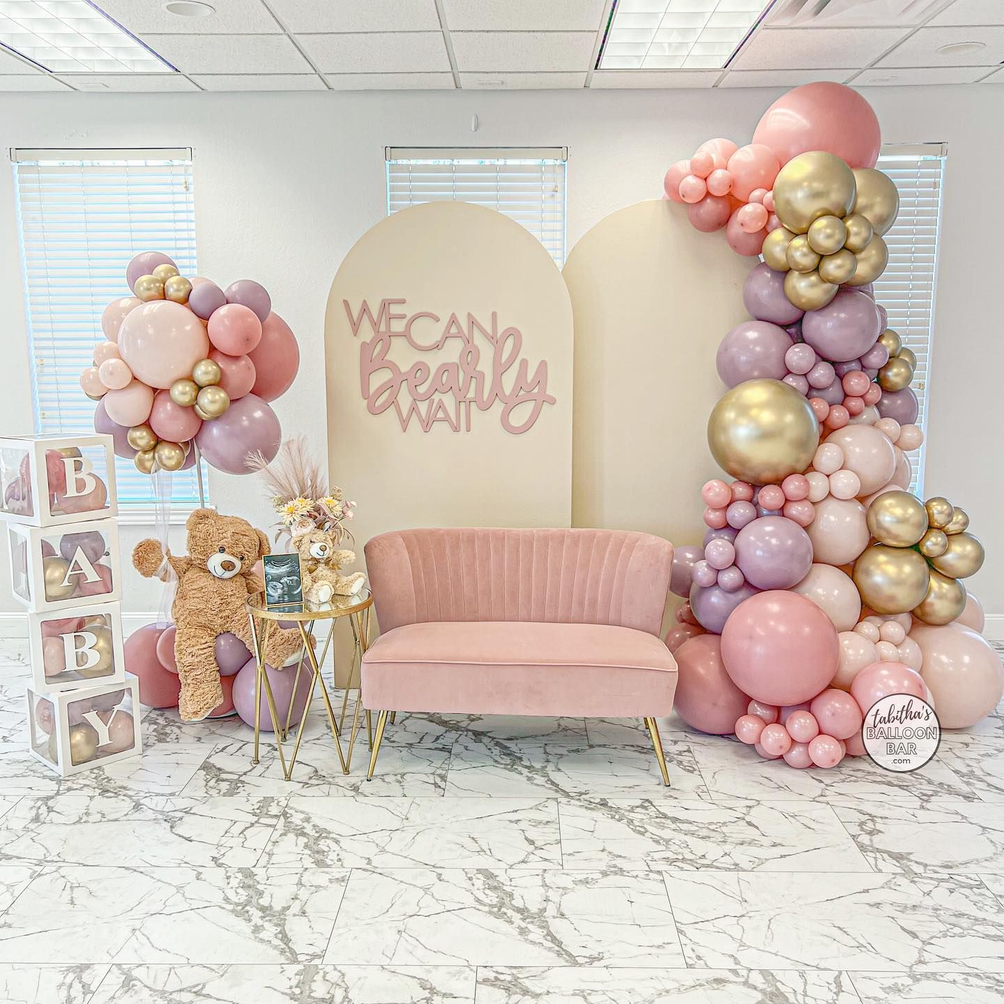 A room filled with balloons , a couch , and a teddy bear.