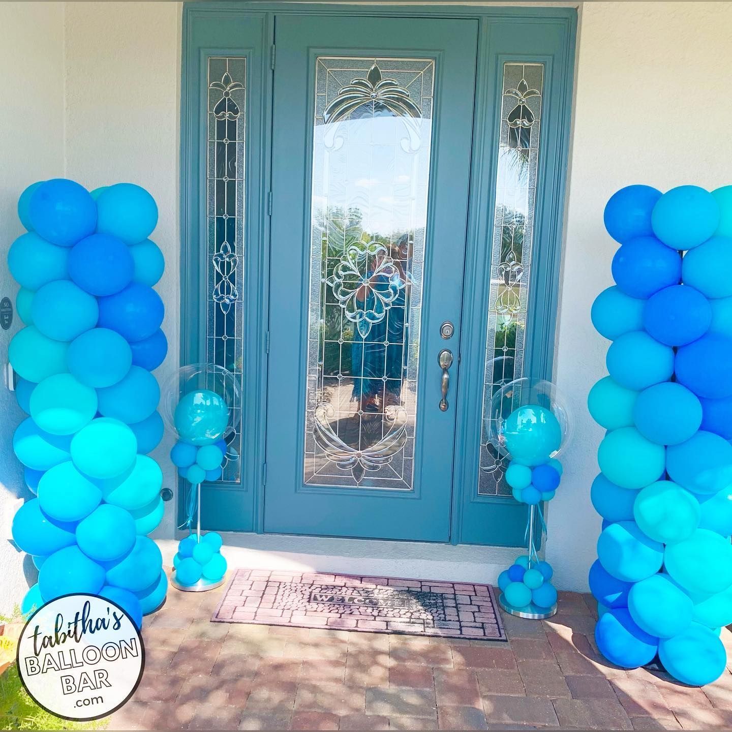 Two columns of blue balloons are in front of a blue door.