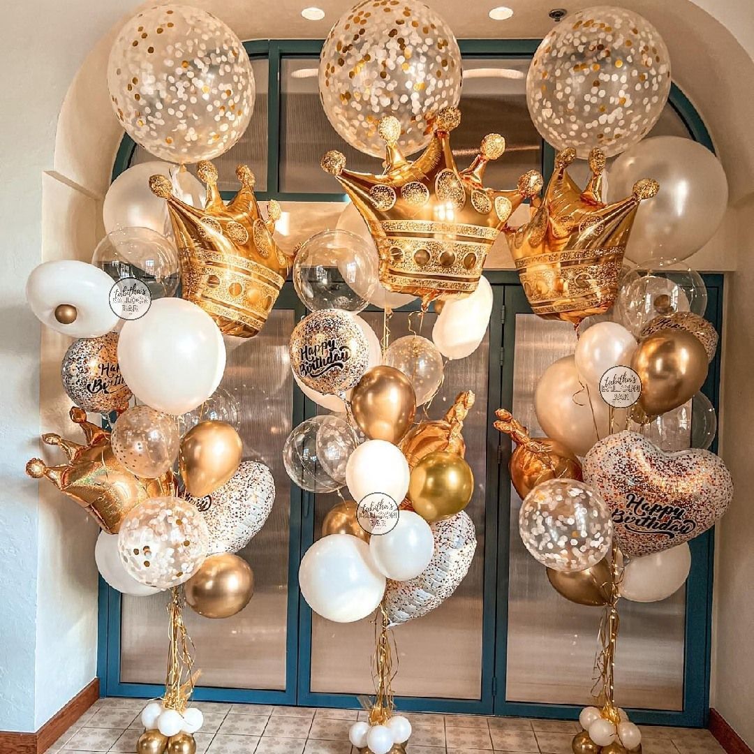 A bunch of balloons with crowns on them are sitting in front of a window.