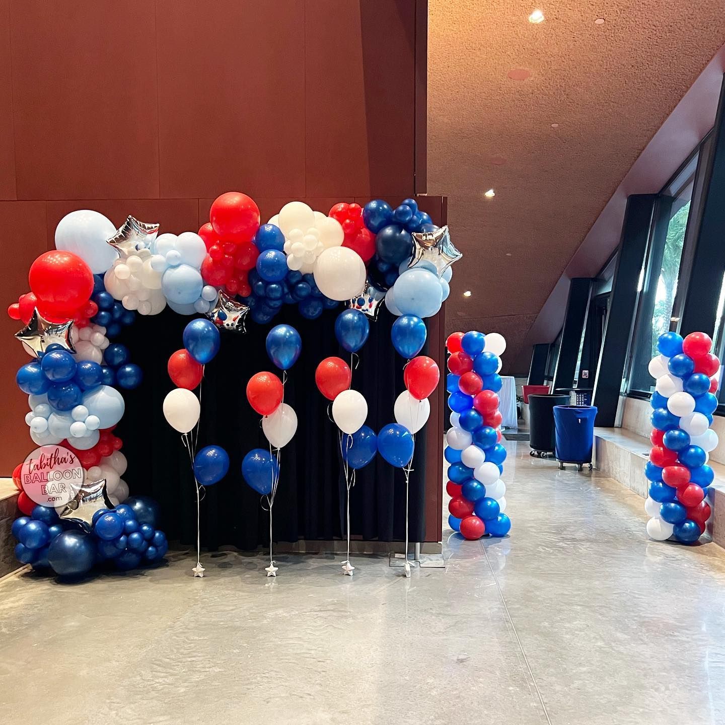 A room filled with red , white and blue balloons