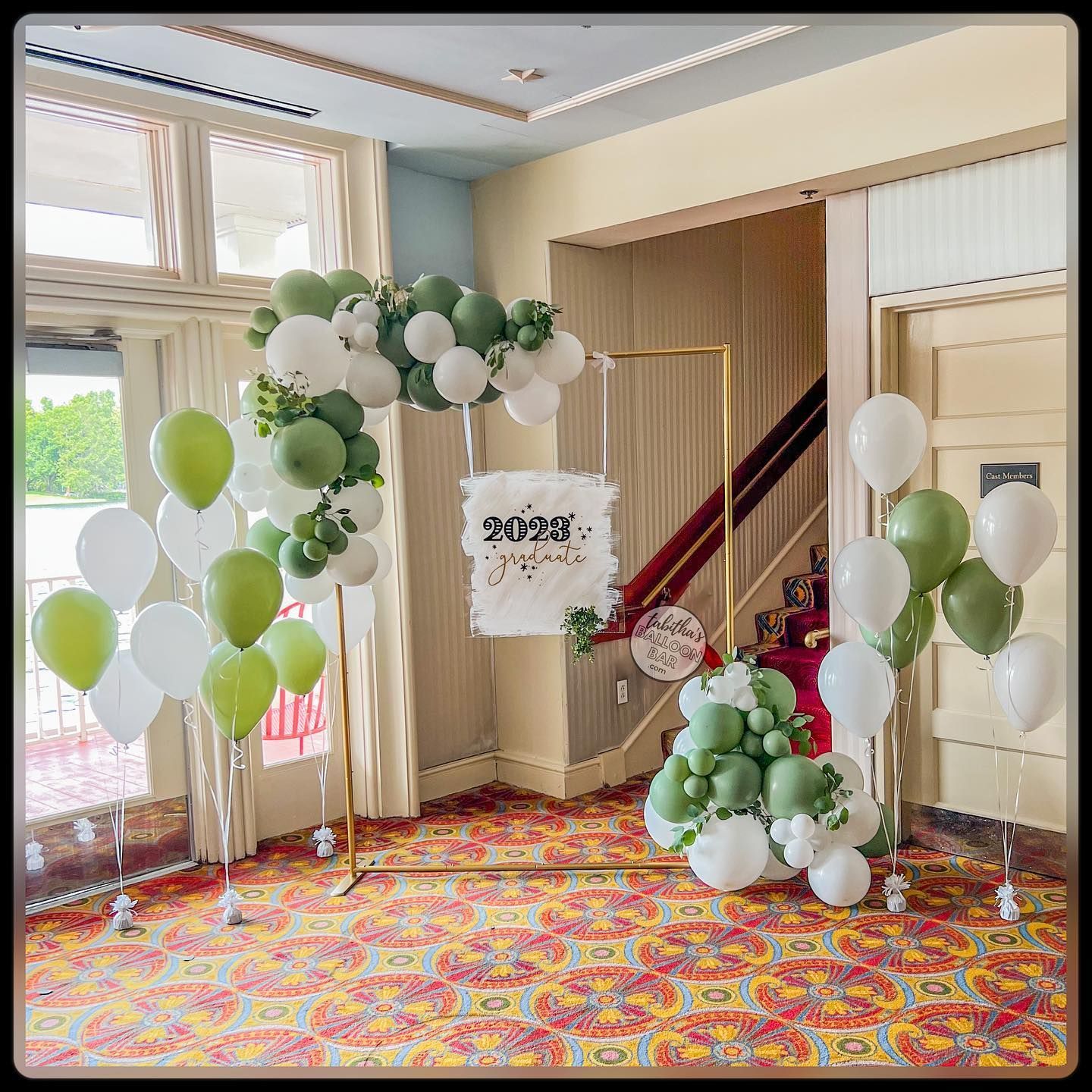 A room decorated with green and white balloons and a sign.