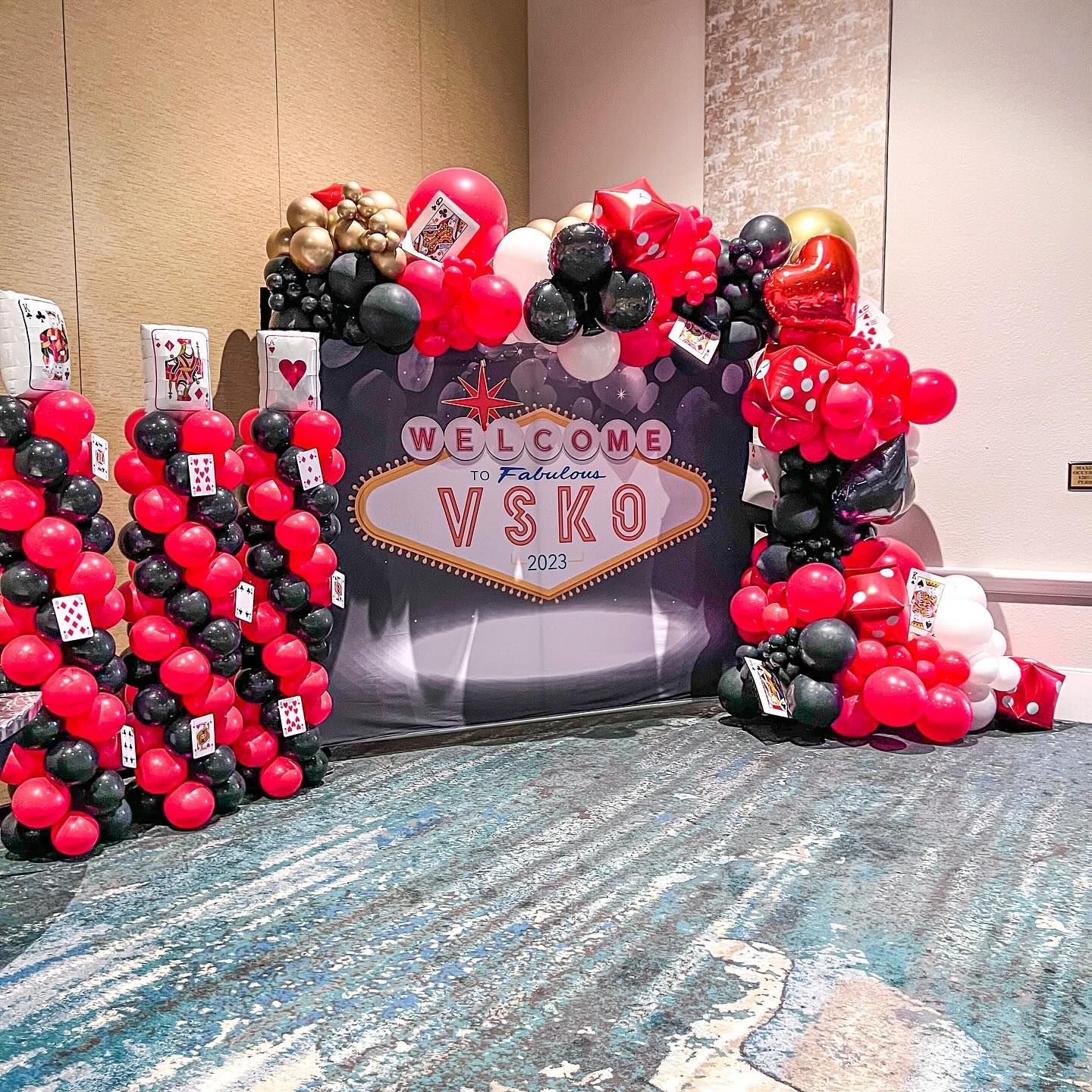 A room decorated with red and black balloons and playing cards.