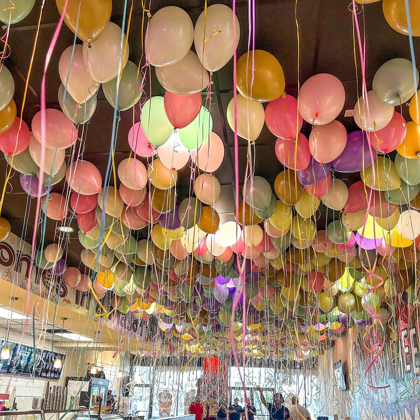 A bunch of balloons are hanging from the ceiling of a room