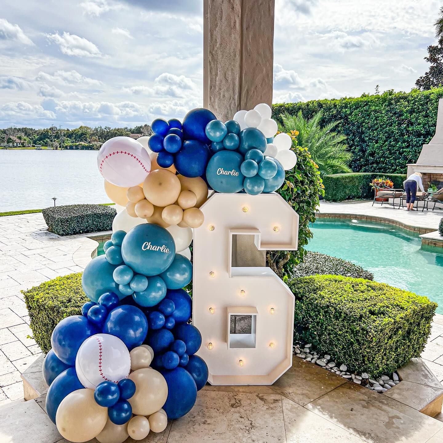 A large number 6 is surrounded by blue and white balloons.