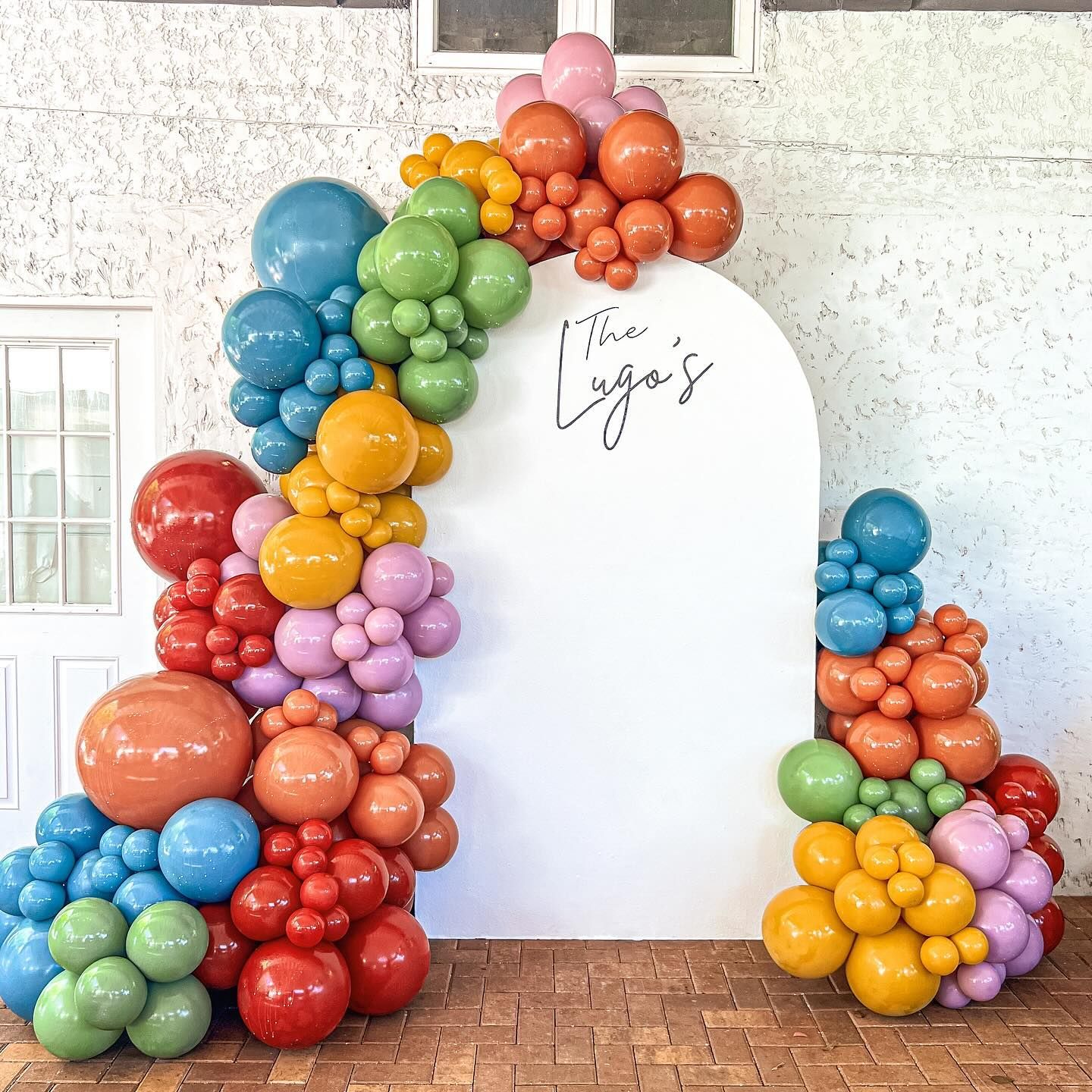 A bunch of colorful balloons are sitting on top of a white wall.