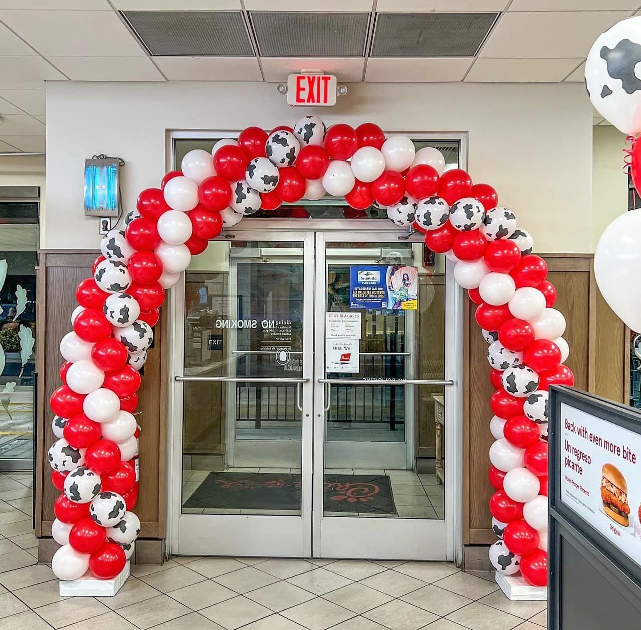 A red and white balloon arch in front of an exit sign