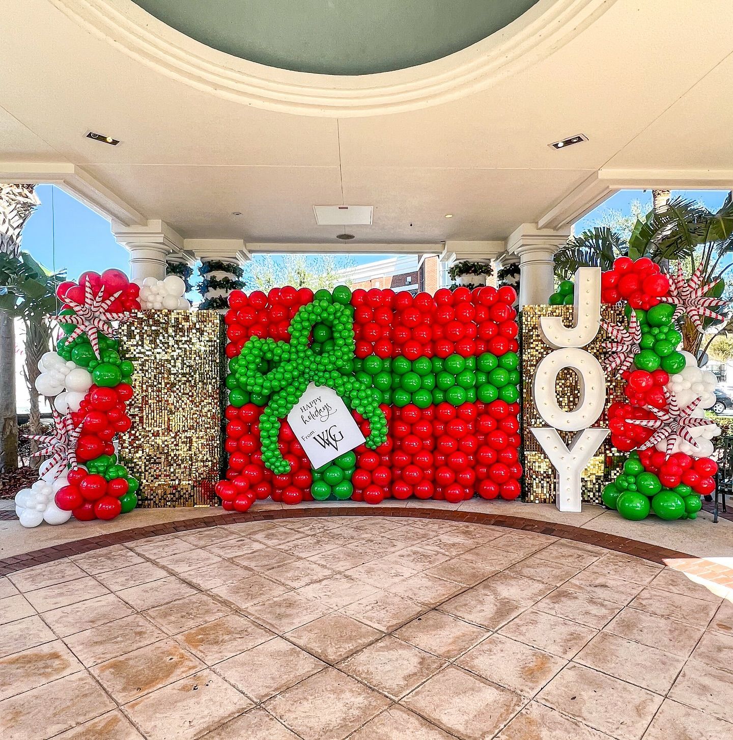 large balloon christmas balloon decor display showing a large present with the word joy