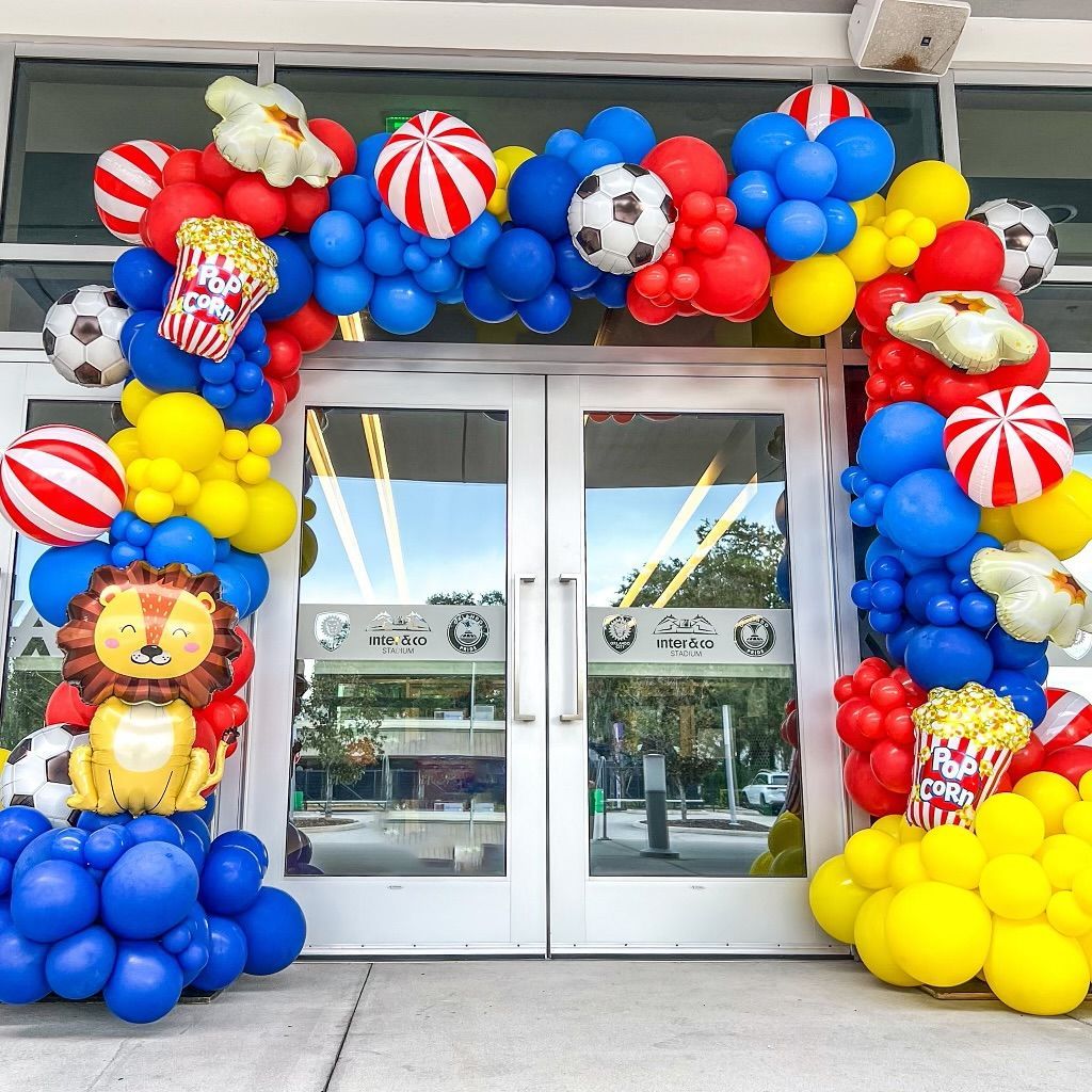 A lion balloon is surrounded by balloons in front of a building.