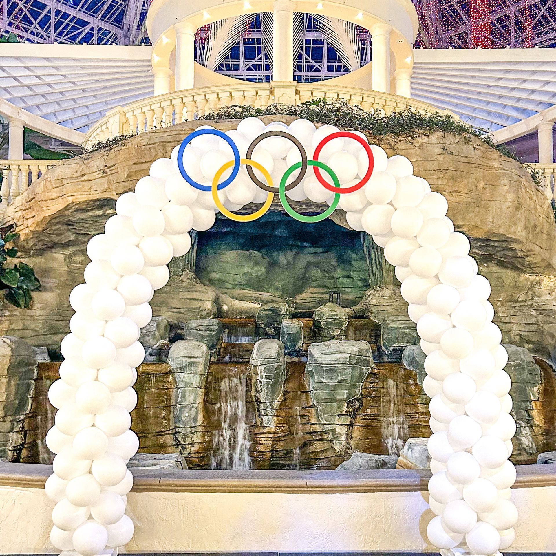 A white balloon arch with the olympic rings on it