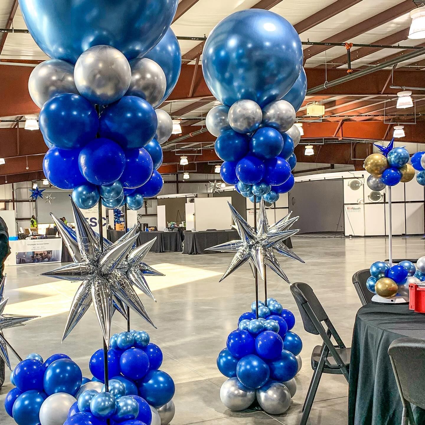 A bunch of blue and silver balloons are sitting on top of each other in a room.