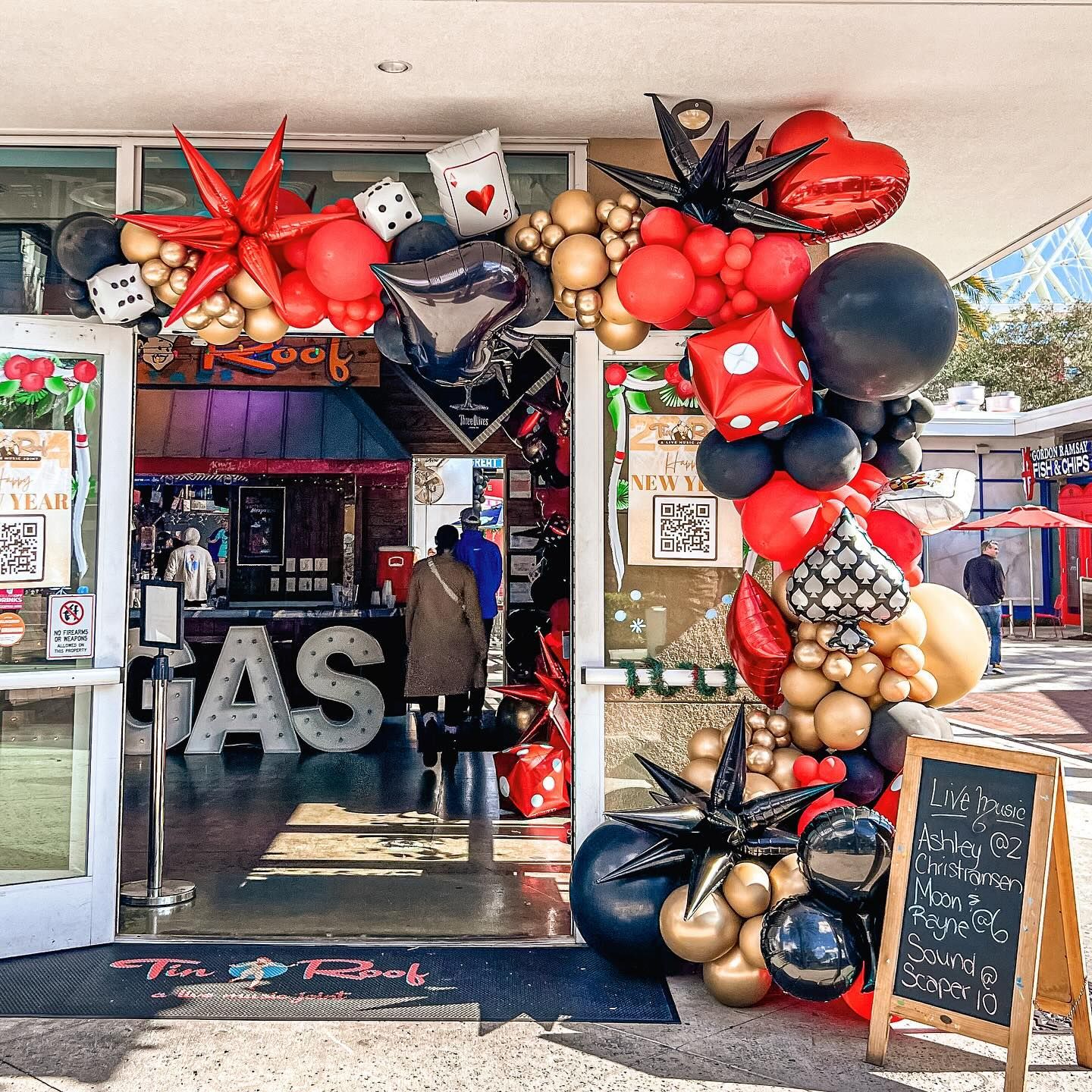 A store front decorated with red , black and gold balloons.