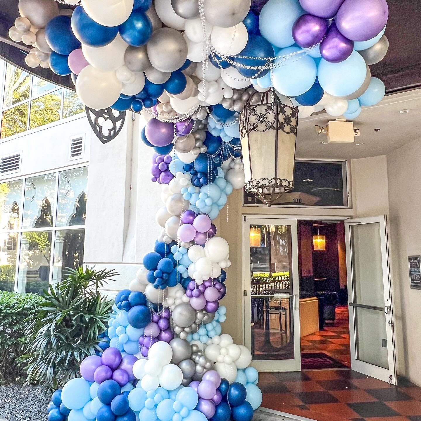 A bunch of blue and purple balloons are hanging from the ceiling