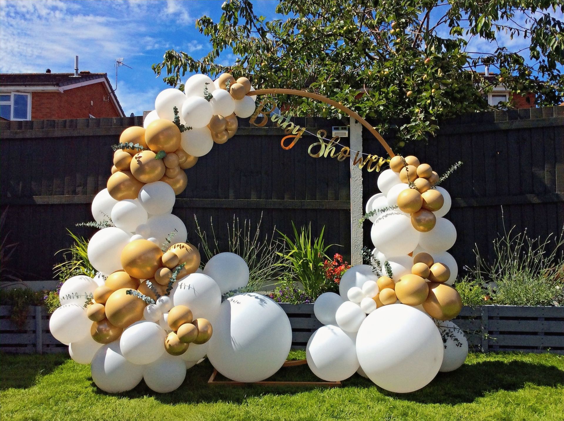 a bunch of white and gold balloons are sitting on top of a lush green field .