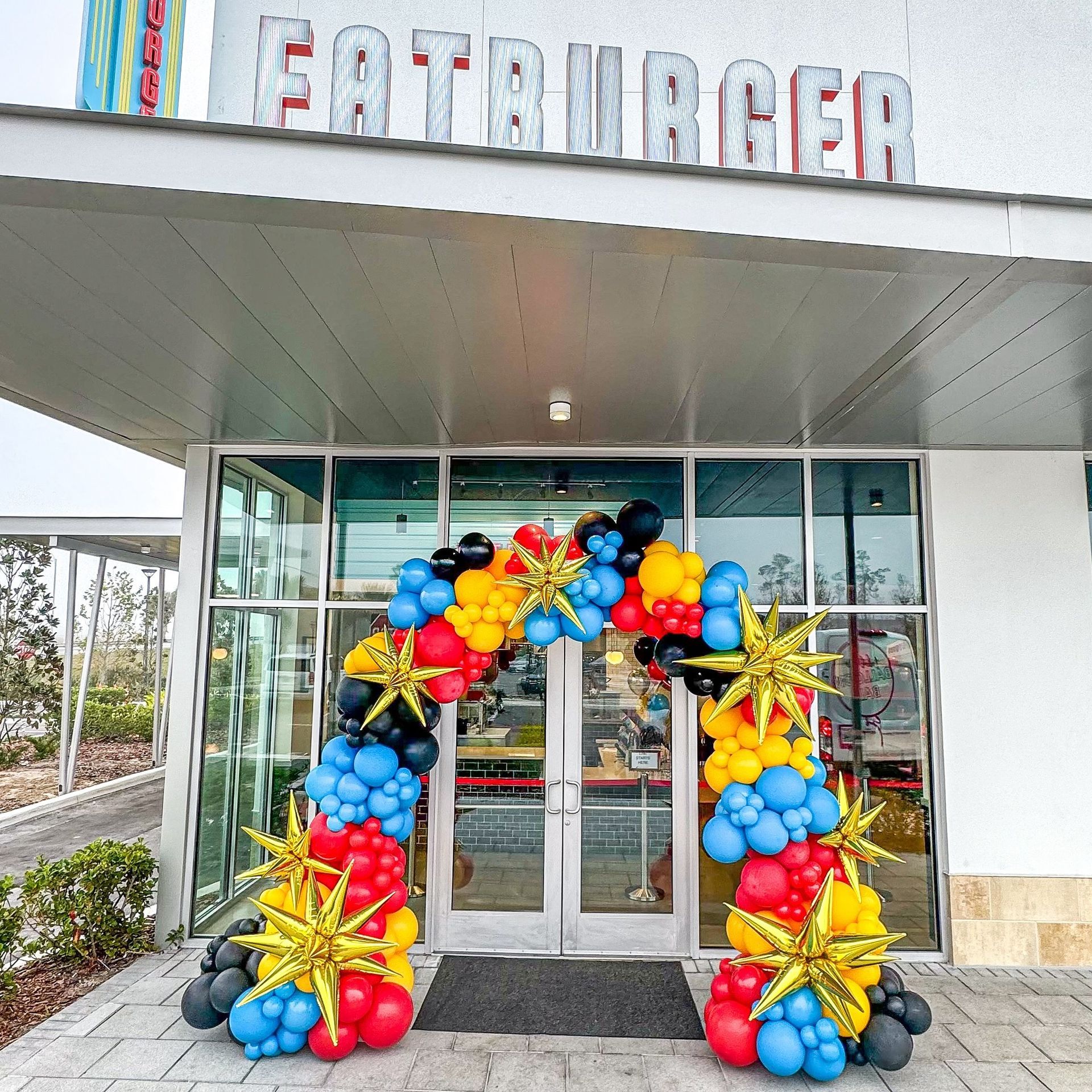 A restaurant with a large arch of balloons in front of it