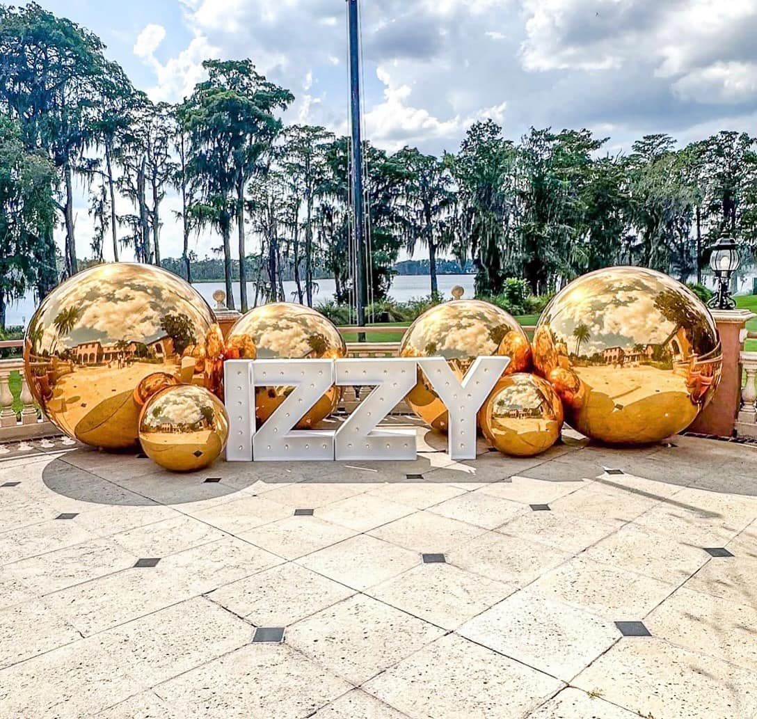 A large sign that says izzy is surrounded by gold balls.