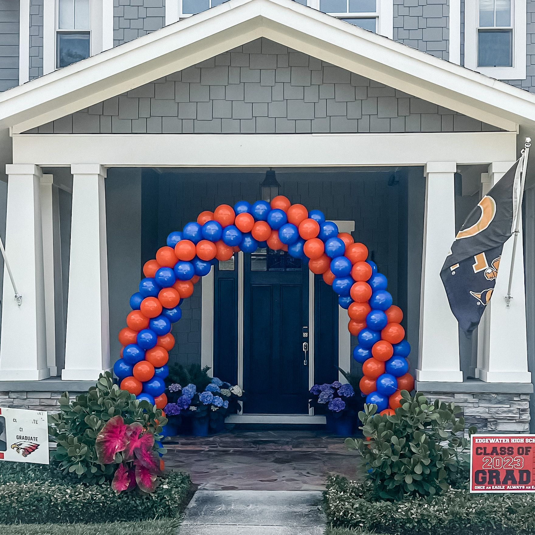 A blue and orange balloon arch in front of a house