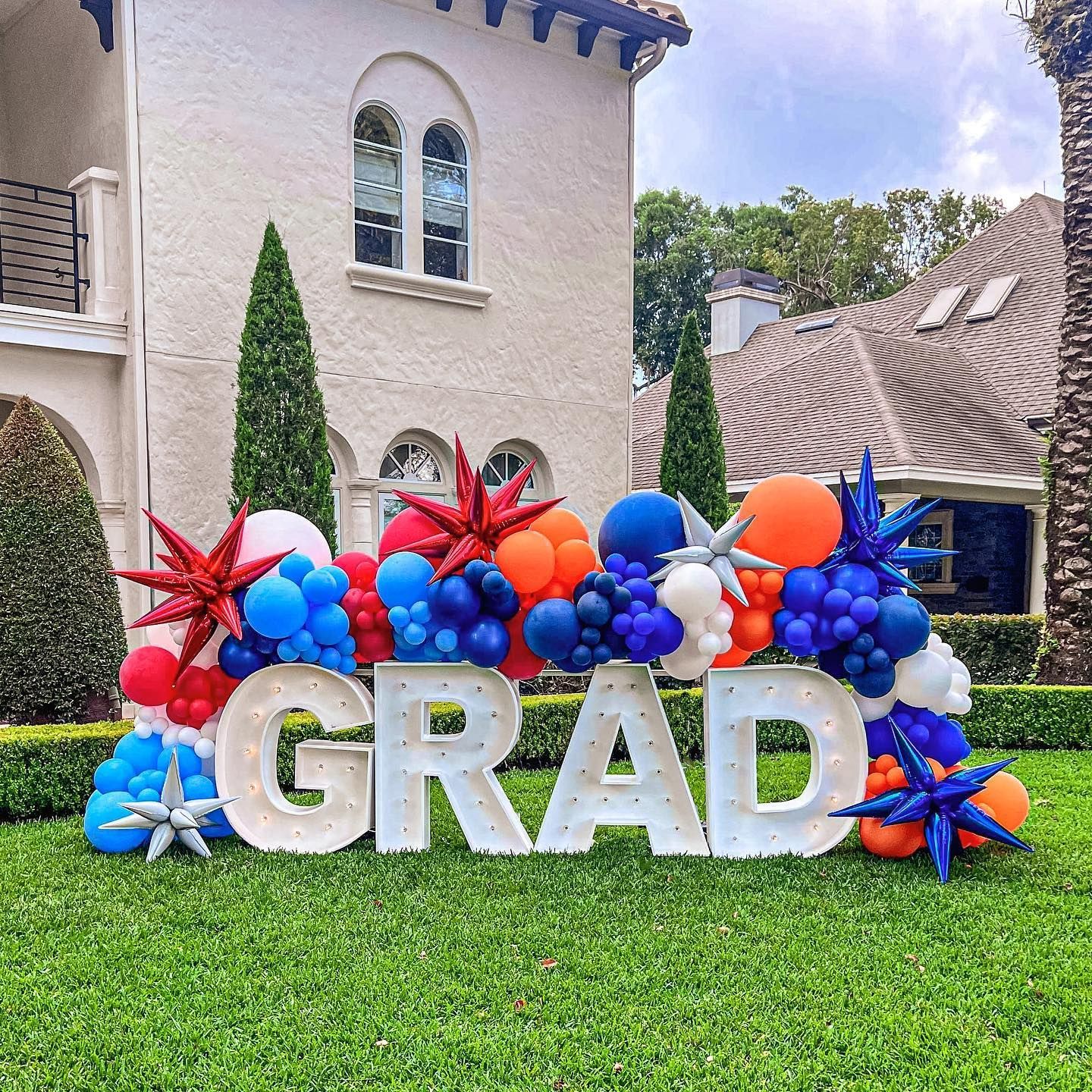 A sign that says grad is surrounded by balloons in front of a house.