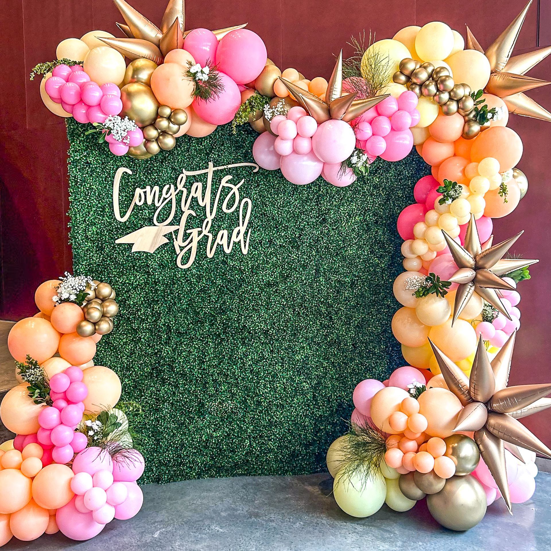 A wall decorated with balloons and flowers for a graduation party.