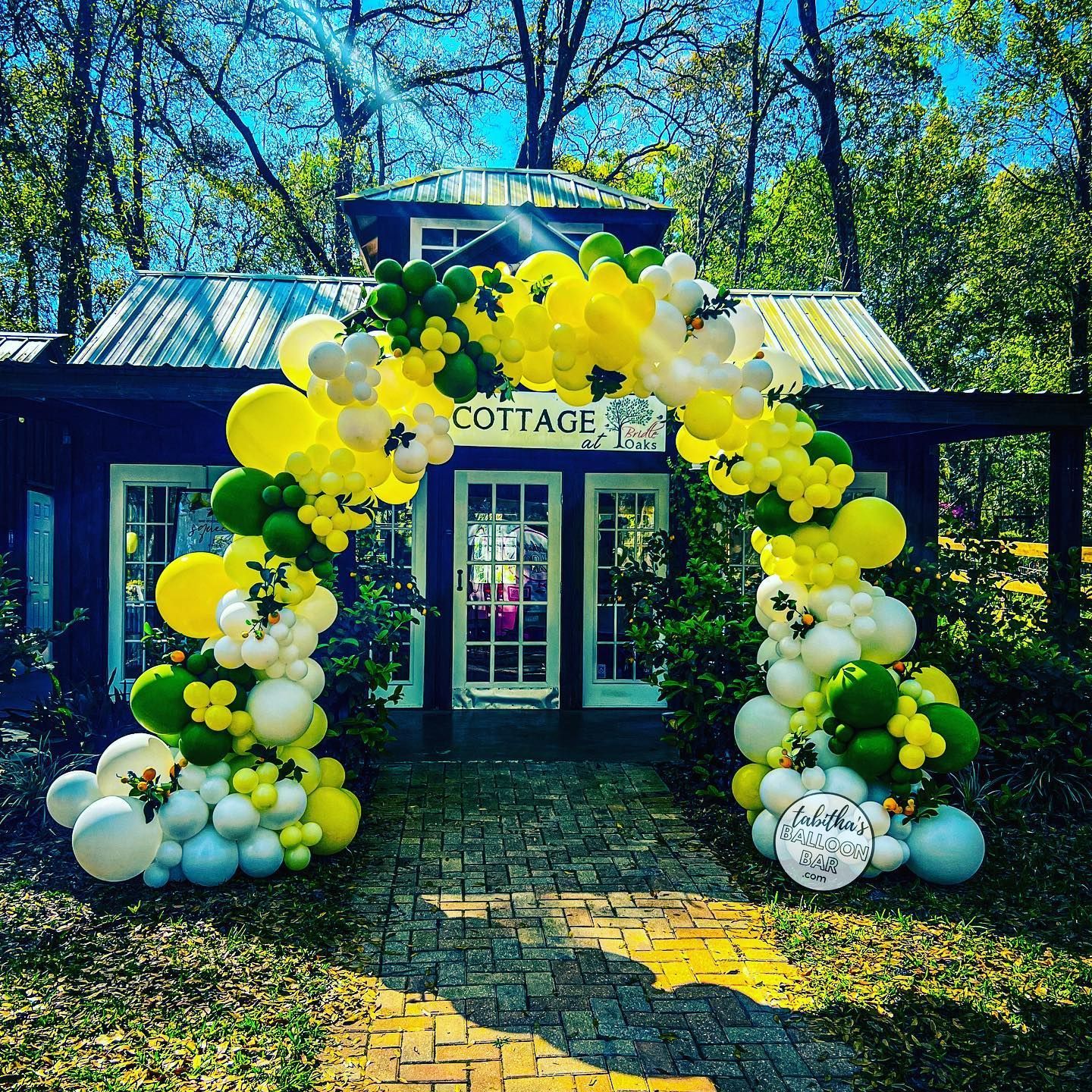 A yellow and green balloon arch is in front of a building.