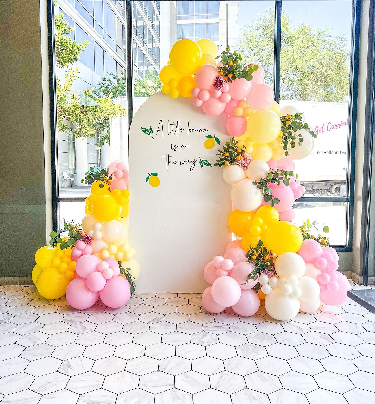 A wall with pink and yellow balloons and flowers on it