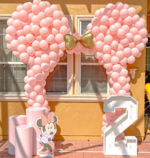 A minnie mouse statue is surrounded by pink balloons and a number 2.