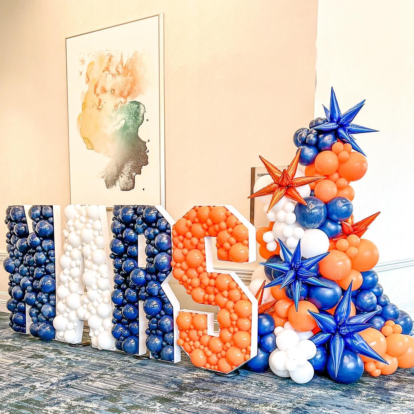 A large letter s made out of balloons in a room.